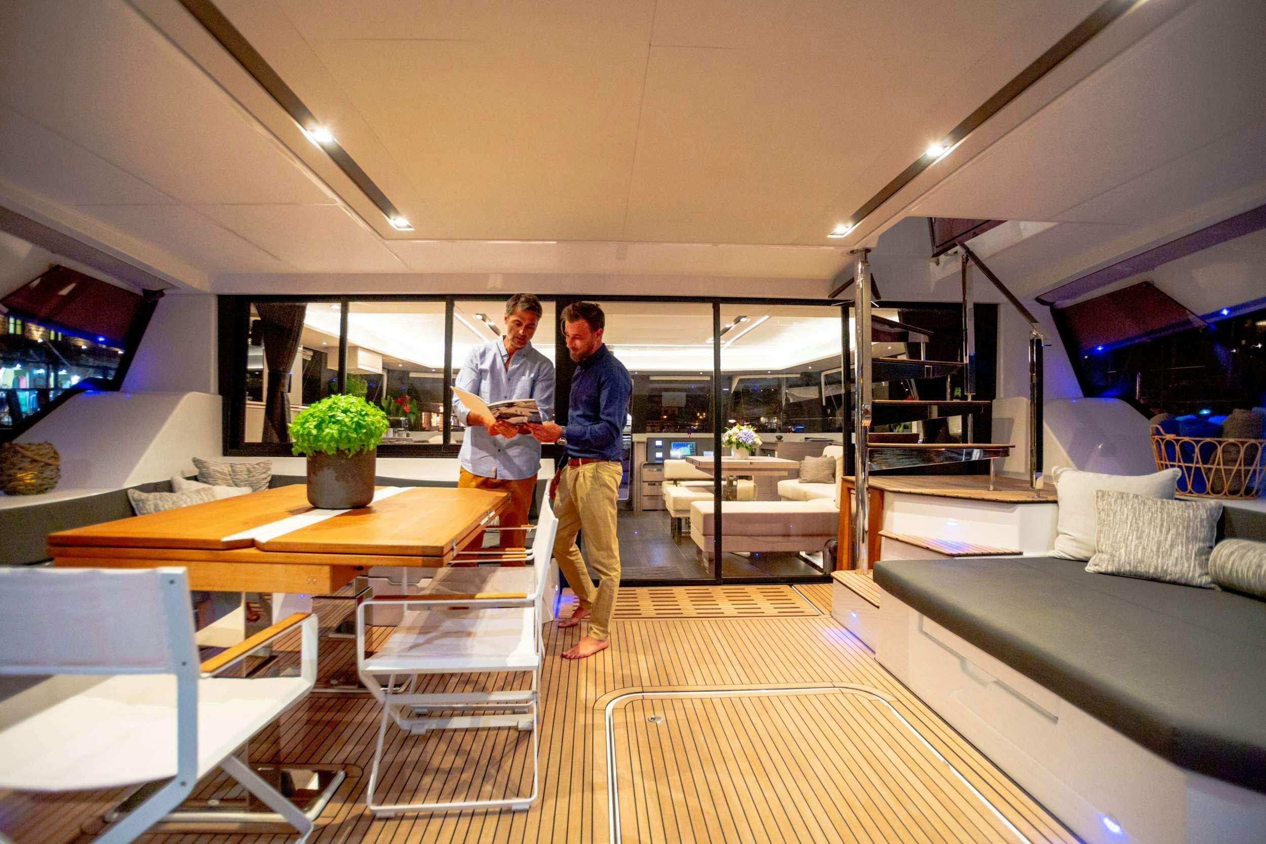 a couple of men standing in a room with a table and chairs aboard ALENA Yacht for Charter