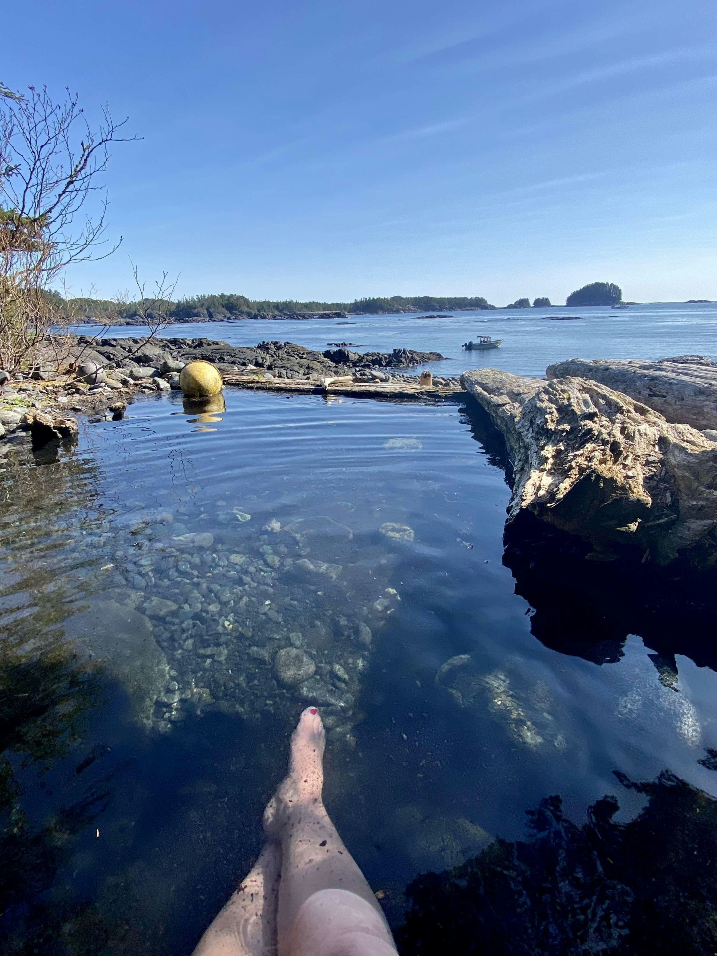 a person's feet on a rocky beach by the water aboard BEAR PAW Yacht for Charter