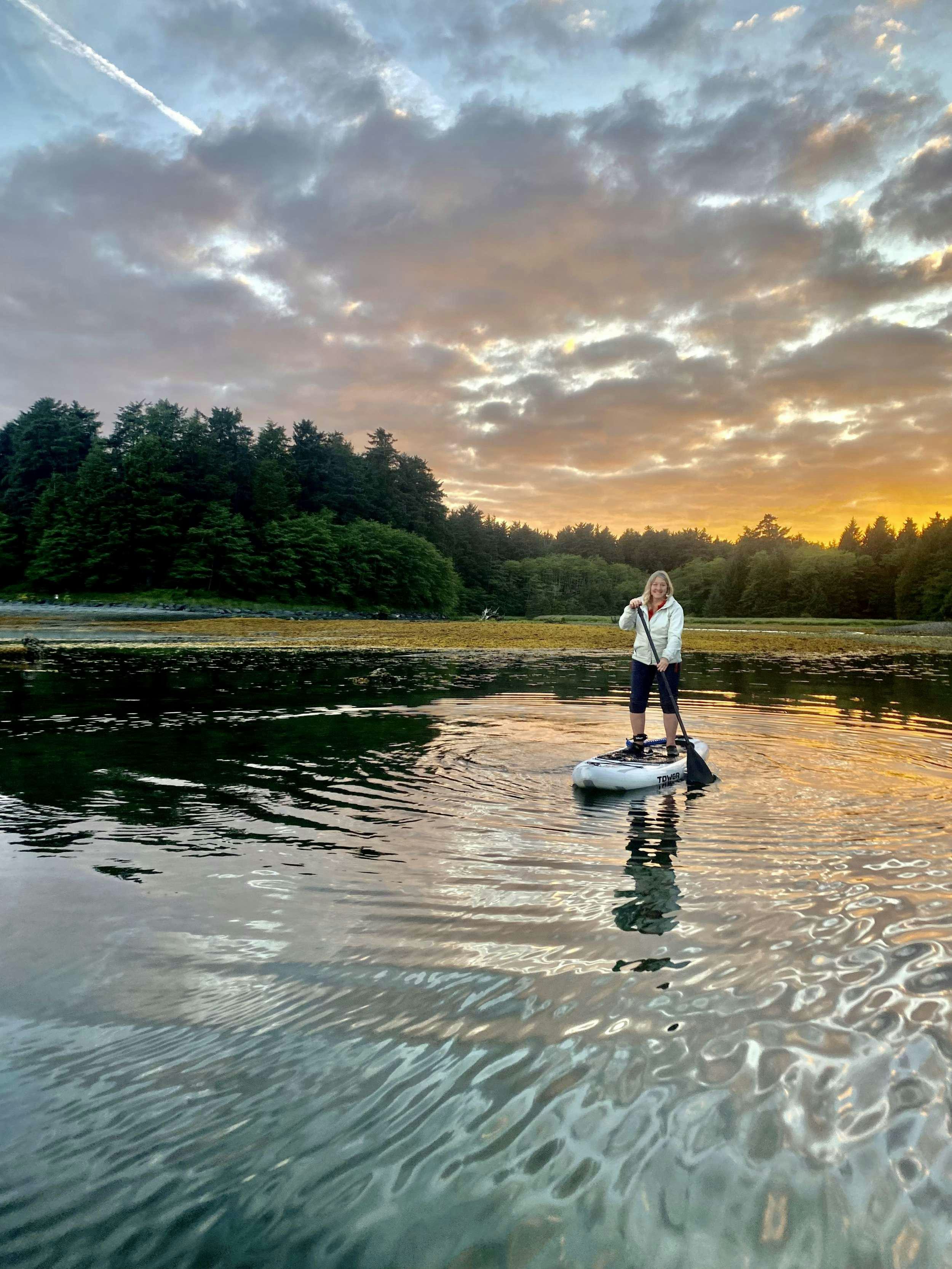 a man standing on a paddle board in a lake aboard BEAR PAW Yacht for Charter