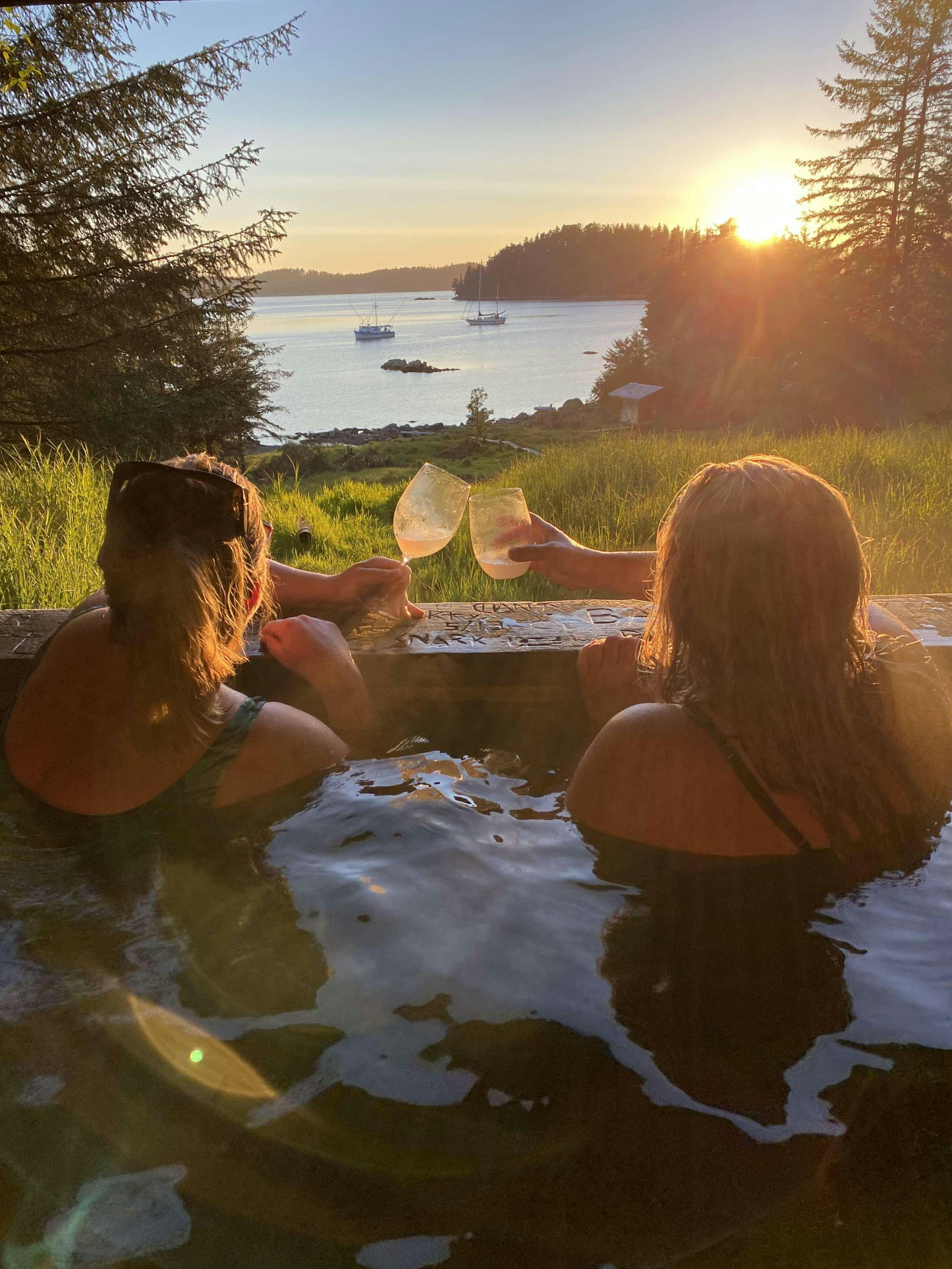 a couple of women sitting in a pool of water with a sunset in the background aboard BEAR PAW Yacht for Charter