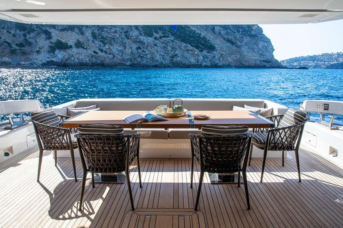 a table and chairs on a deck overlooking a body of water aboard SEVEN Yacht for Charter