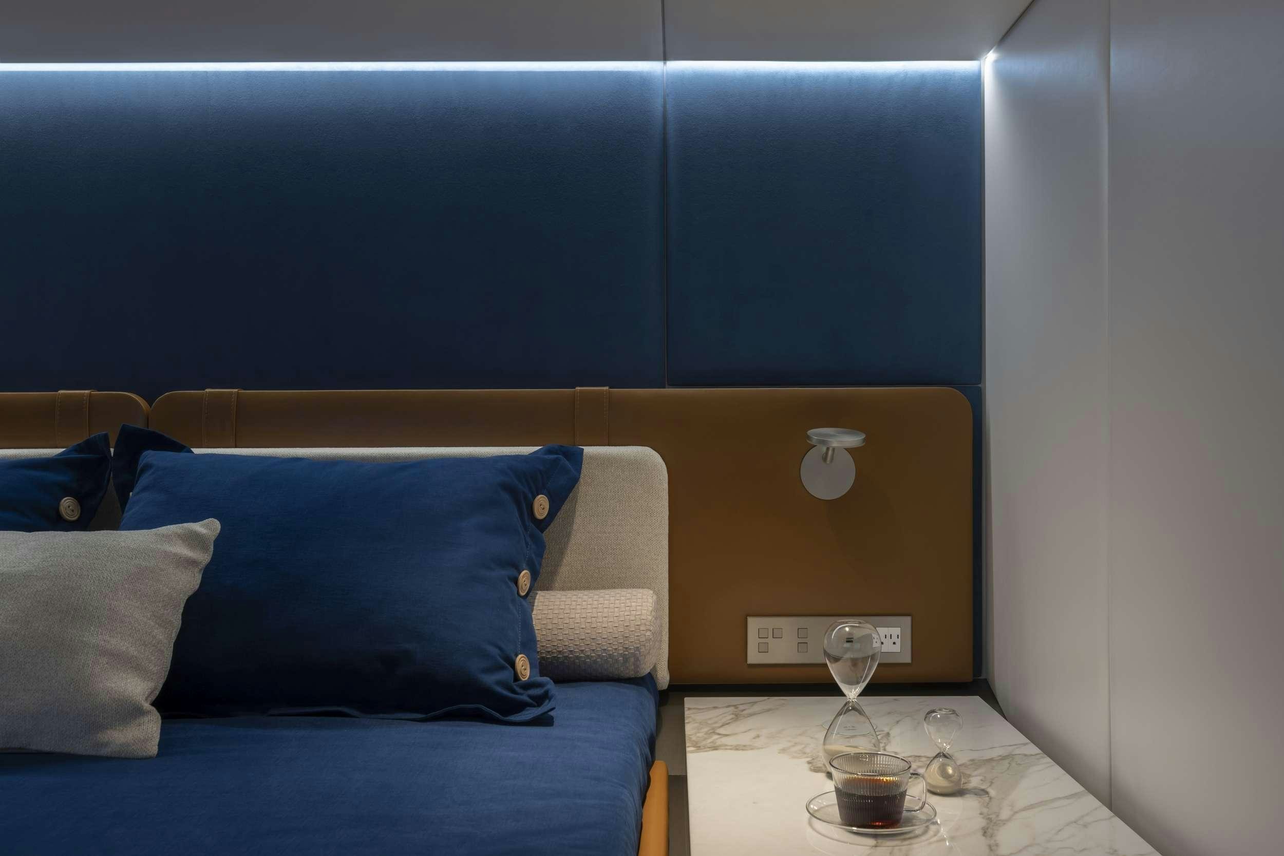 a bed with a blue pillow and a glass of wine on a table aboard PRONTO Yacht for Charter