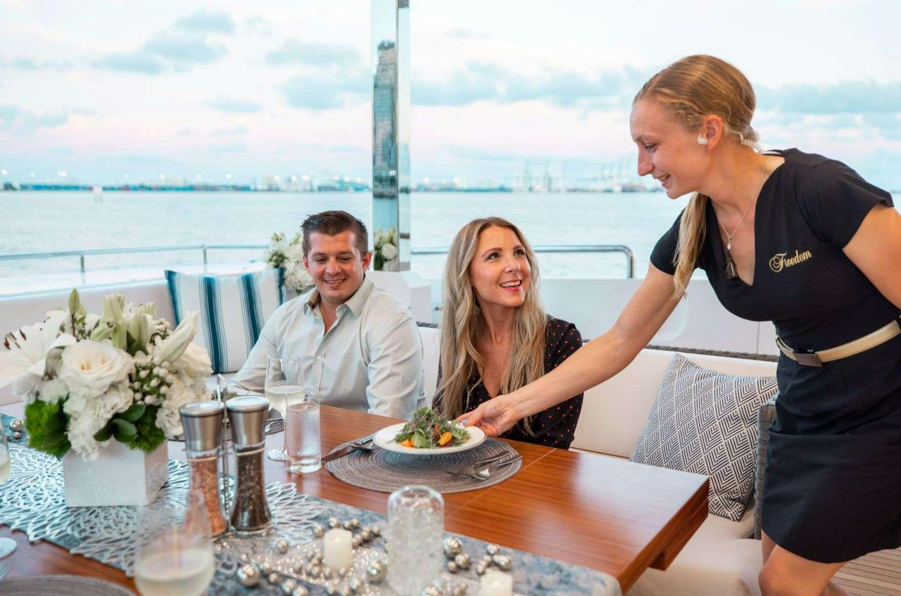 a group of people sitting at a table with food and drinks aboard FREEDOM Yacht for Charter