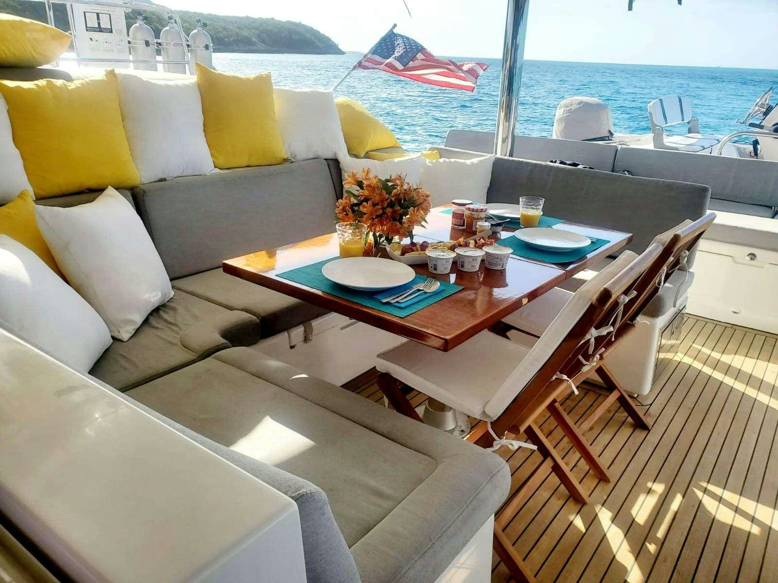a table with chairs and a couch on a boat aboard BLUE CAT Yacht for Charter