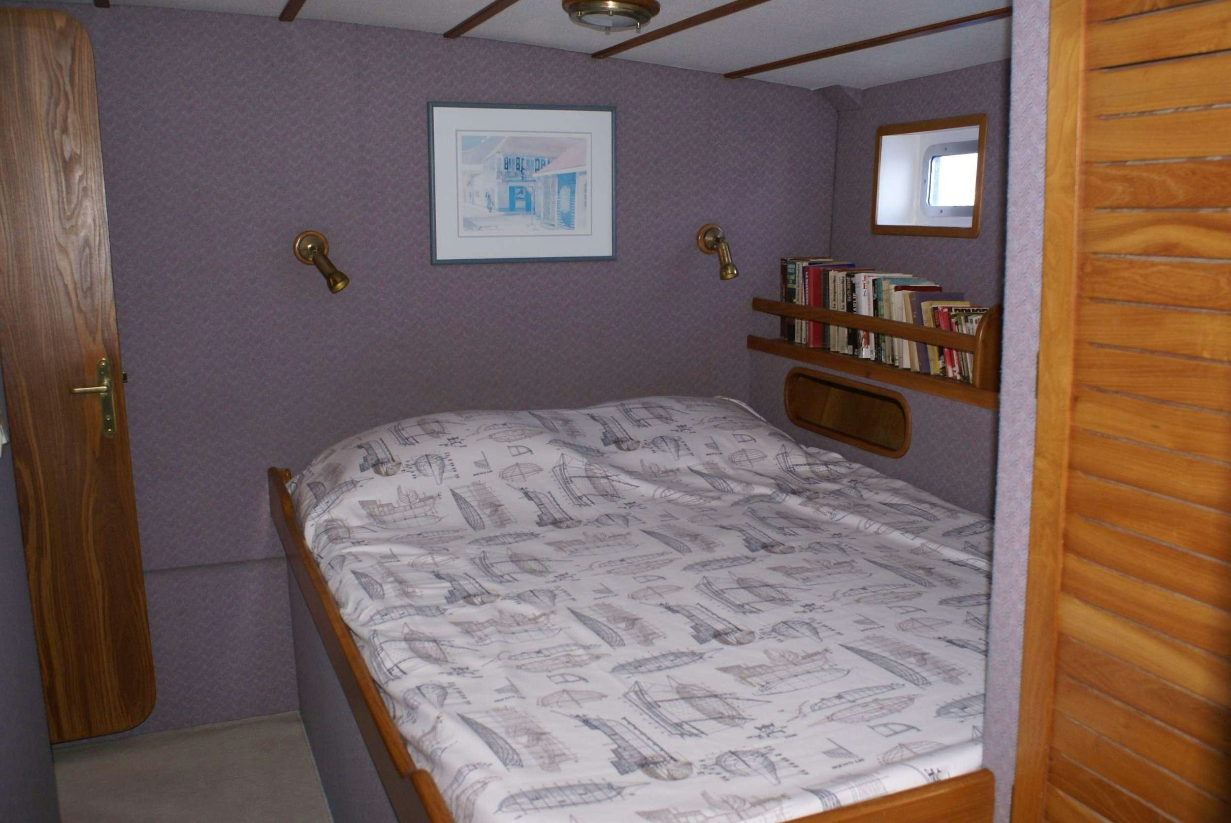 a bedroom with a bed and a bookcase aboard JAIPUR Yacht for Charter