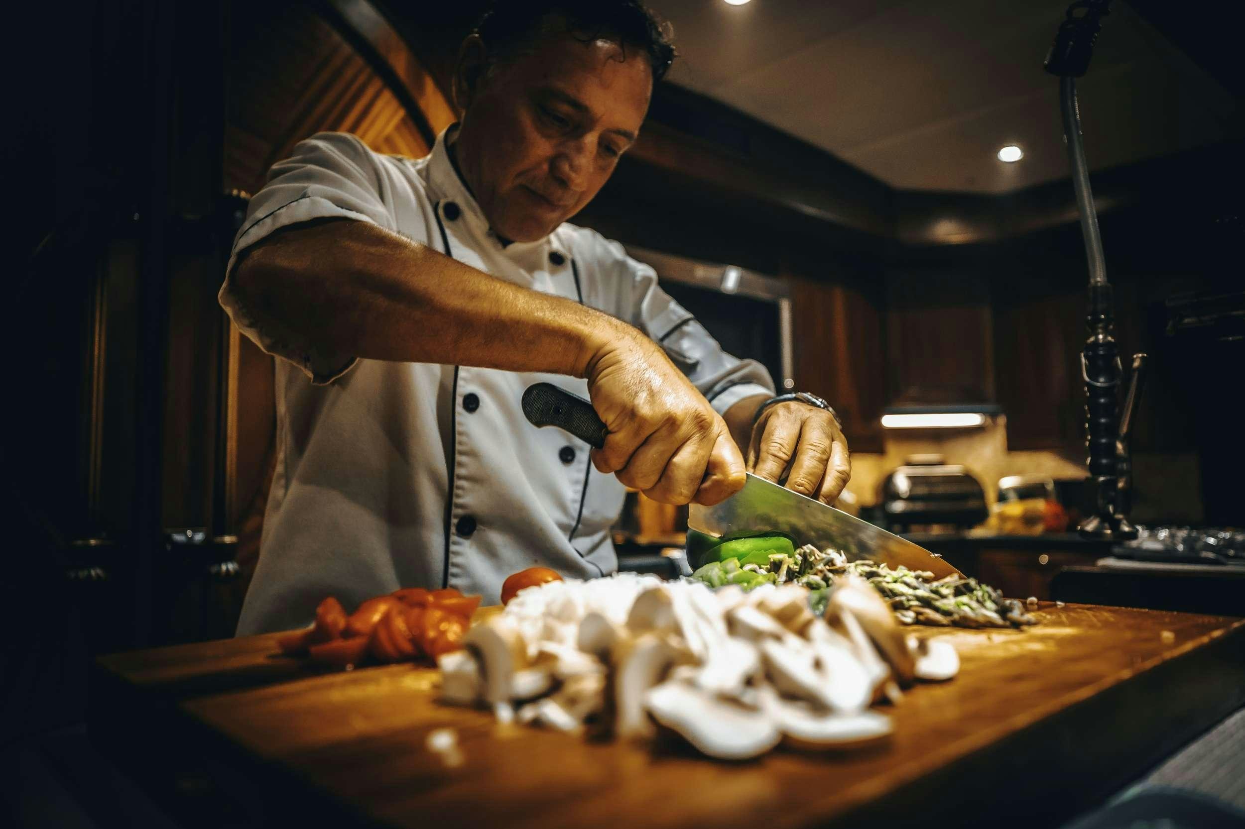 a chef preparing food in a kitchen aboard READY II PLAY Yacht for Charter