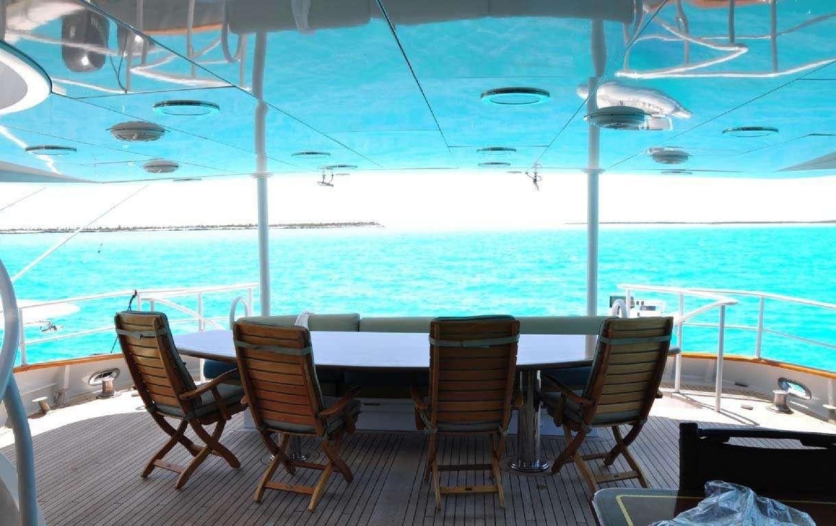 a deck with chairs and tables on it by the ocean aboard READY II PLAY Yacht for Charter