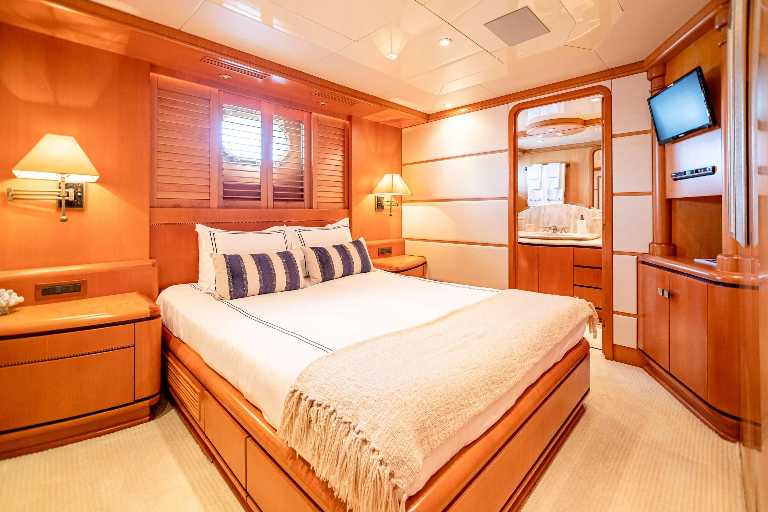 a bedroom with a bed and a television on the wall aboard XOXO (118') Yacht for Charter