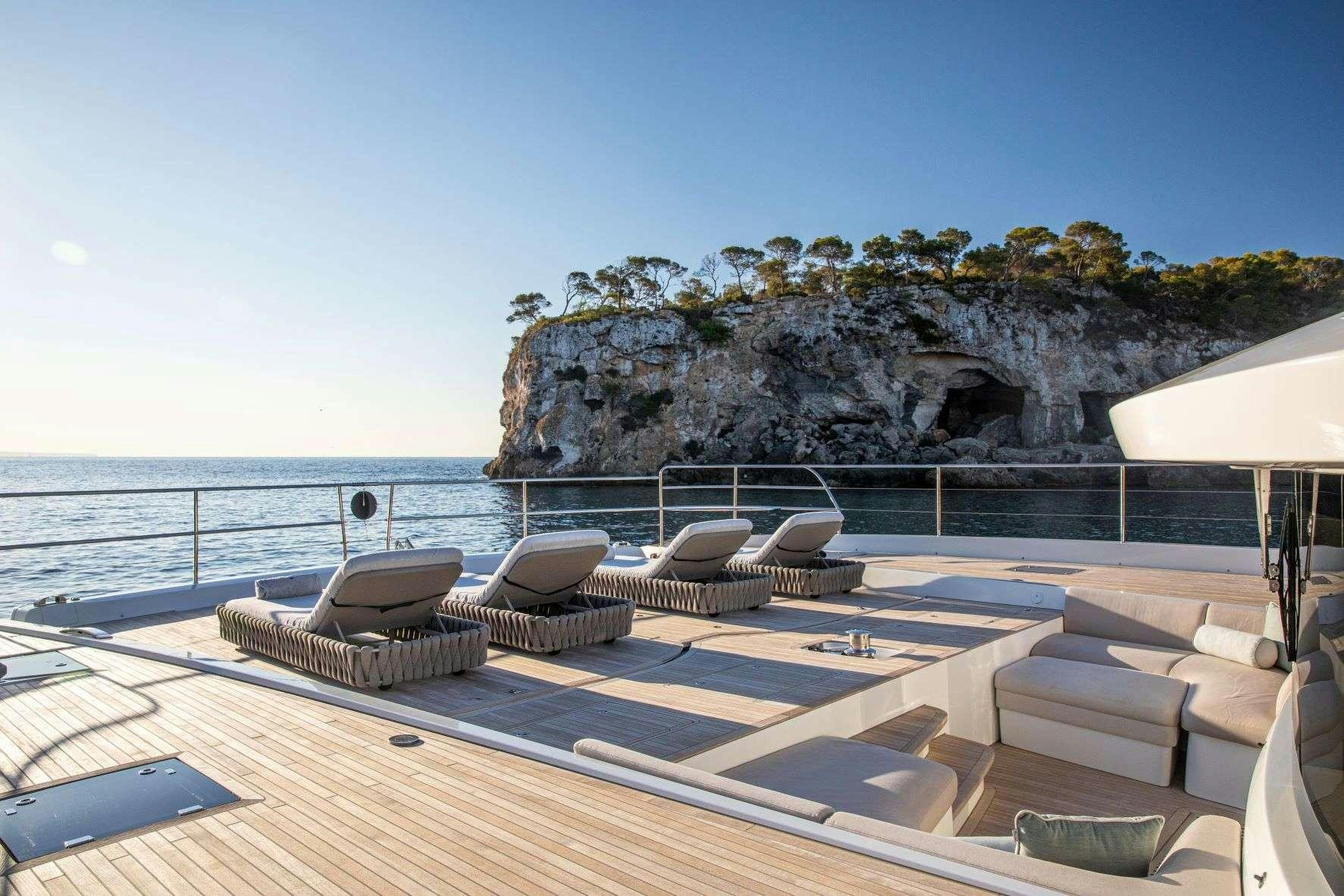 a lounge area with chairs and a rock formation in the background aboard SASTA Yacht for Charter