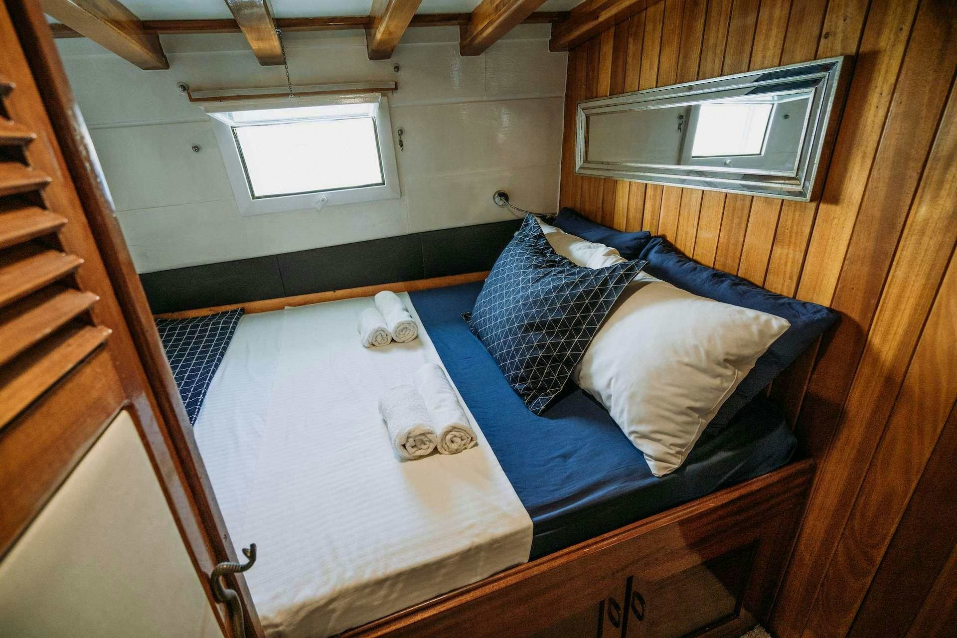 a bed with a blue sheet aboard BEYAZ LALE Yacht for Charter