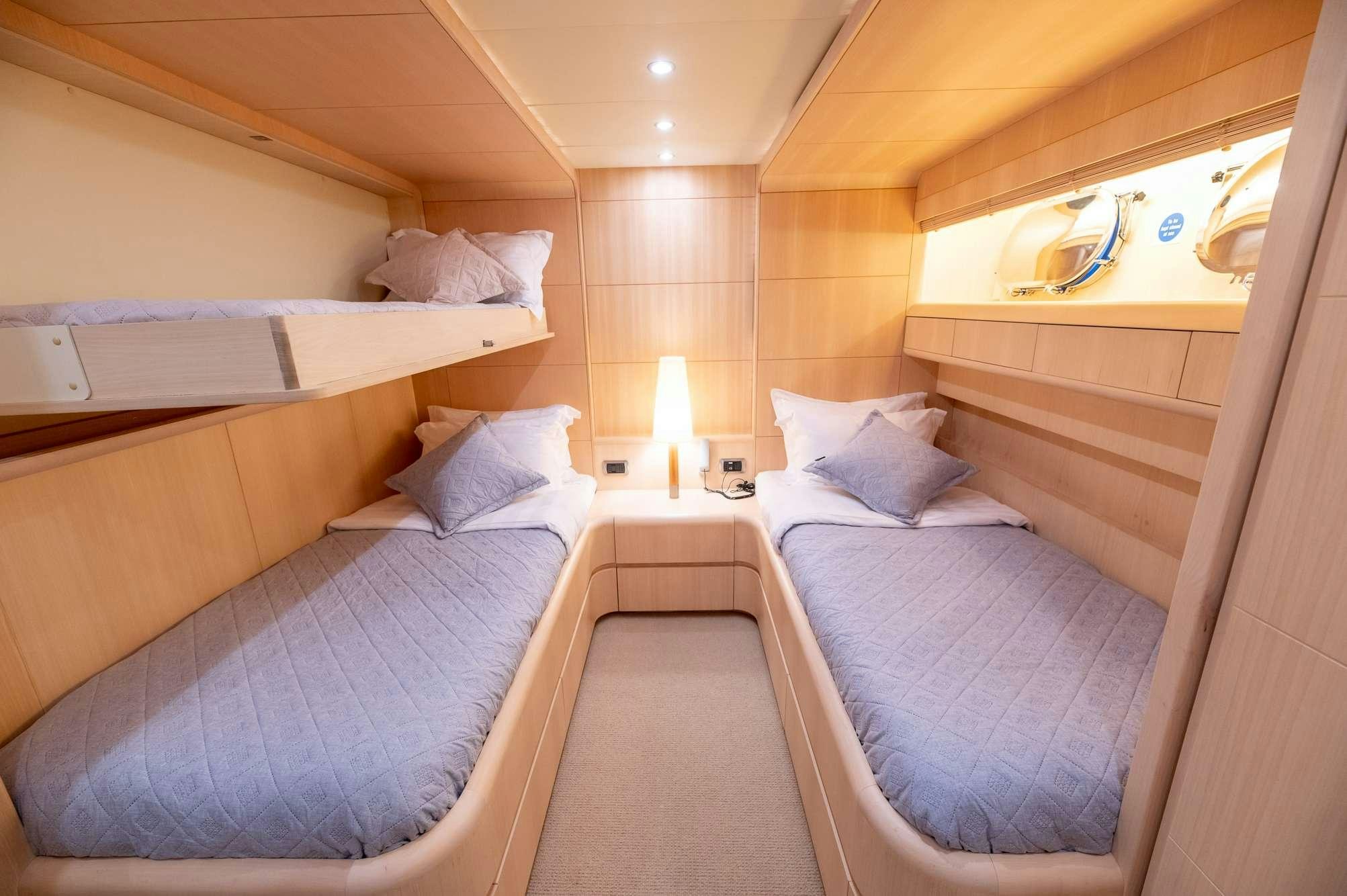 a room with beds and a lamp aboard PEREAKI II Yacht for Charter