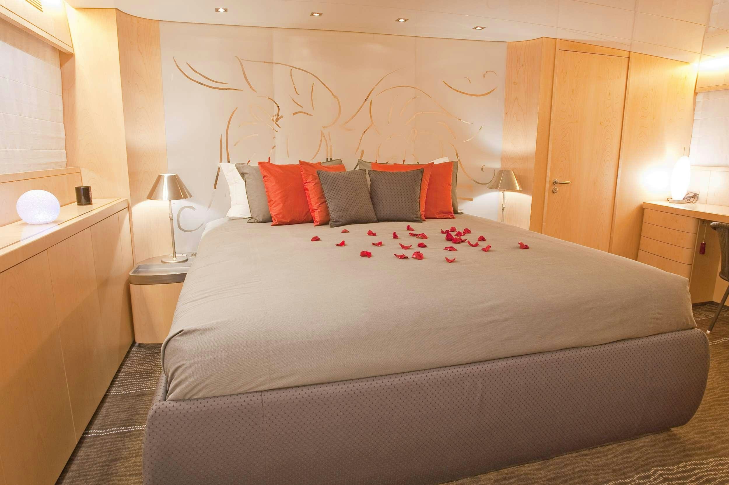 a bed with a white comforter and red pillows aboard COCA VI Yacht for Charter