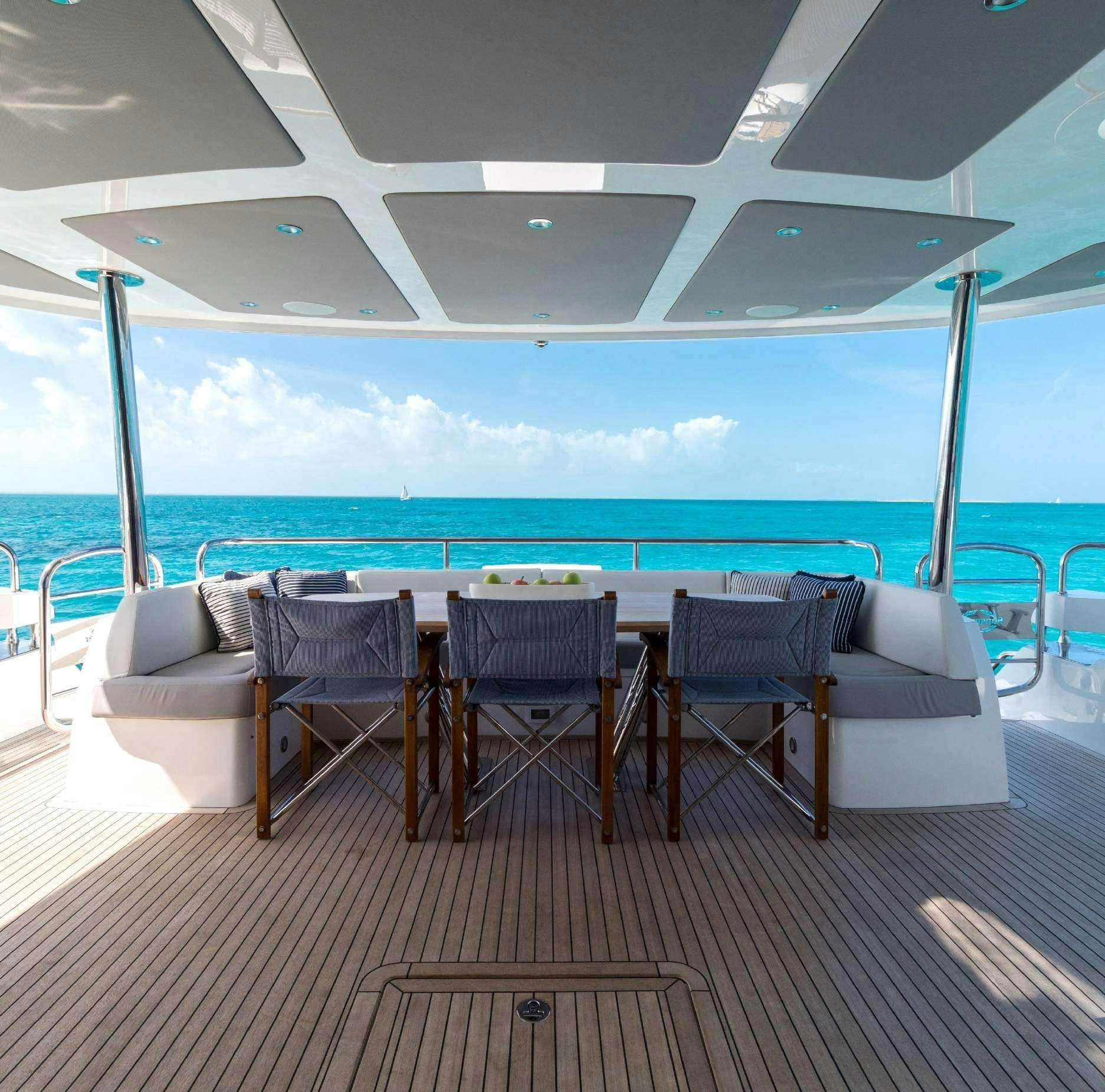 a table and chairs on a deck overlooking the ocean aboard SYNERGY Yacht for Charter
