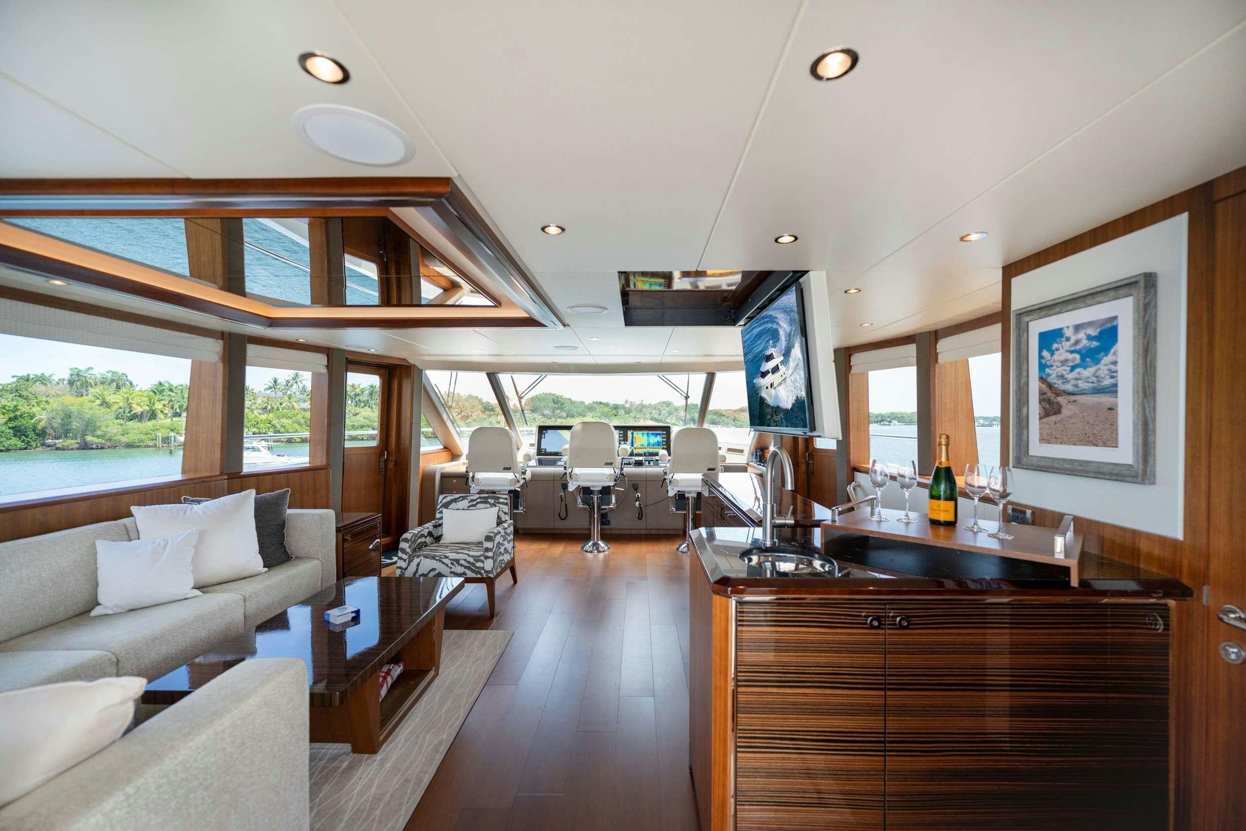 a room with a large window and a wood table with chairs and a large window with a view aboard ZEPHYR Yacht for Charter
