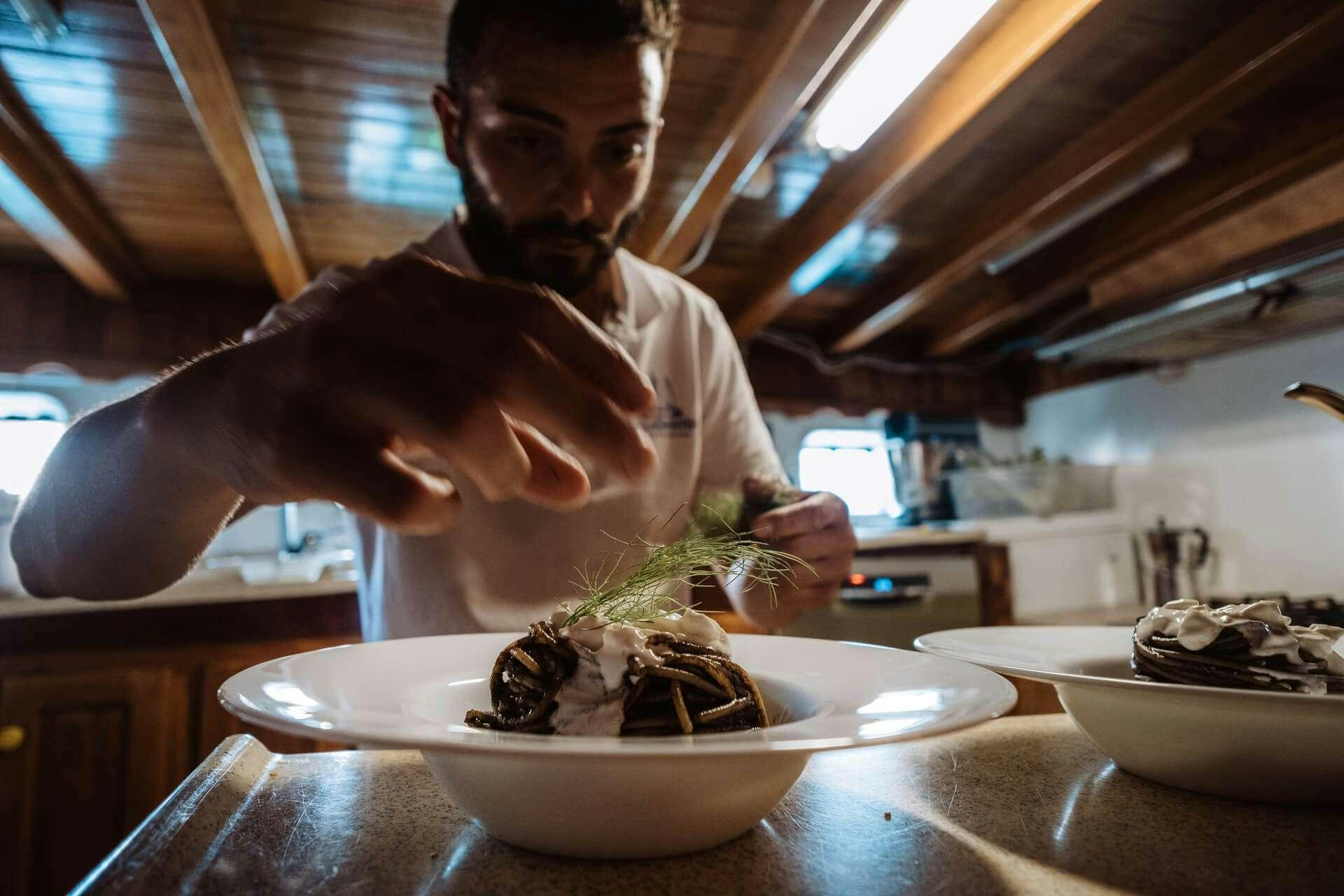 a person pouring a substance into a bowl of food aboard HANDE CAPO GALERA Yacht for Charter