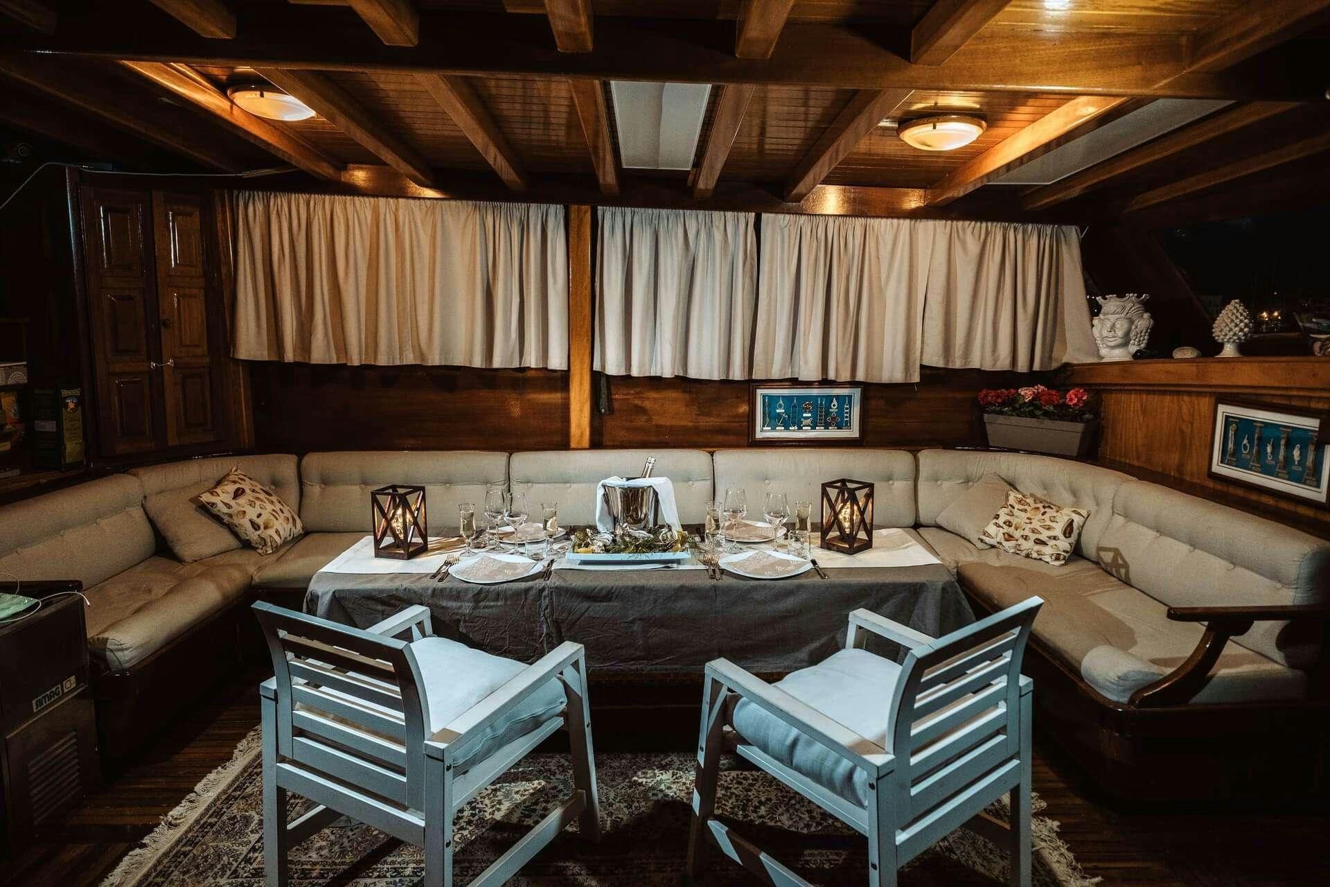 a room with a table chairs and a couch aboard HANDE CAPO GALERA Yacht for Charter
