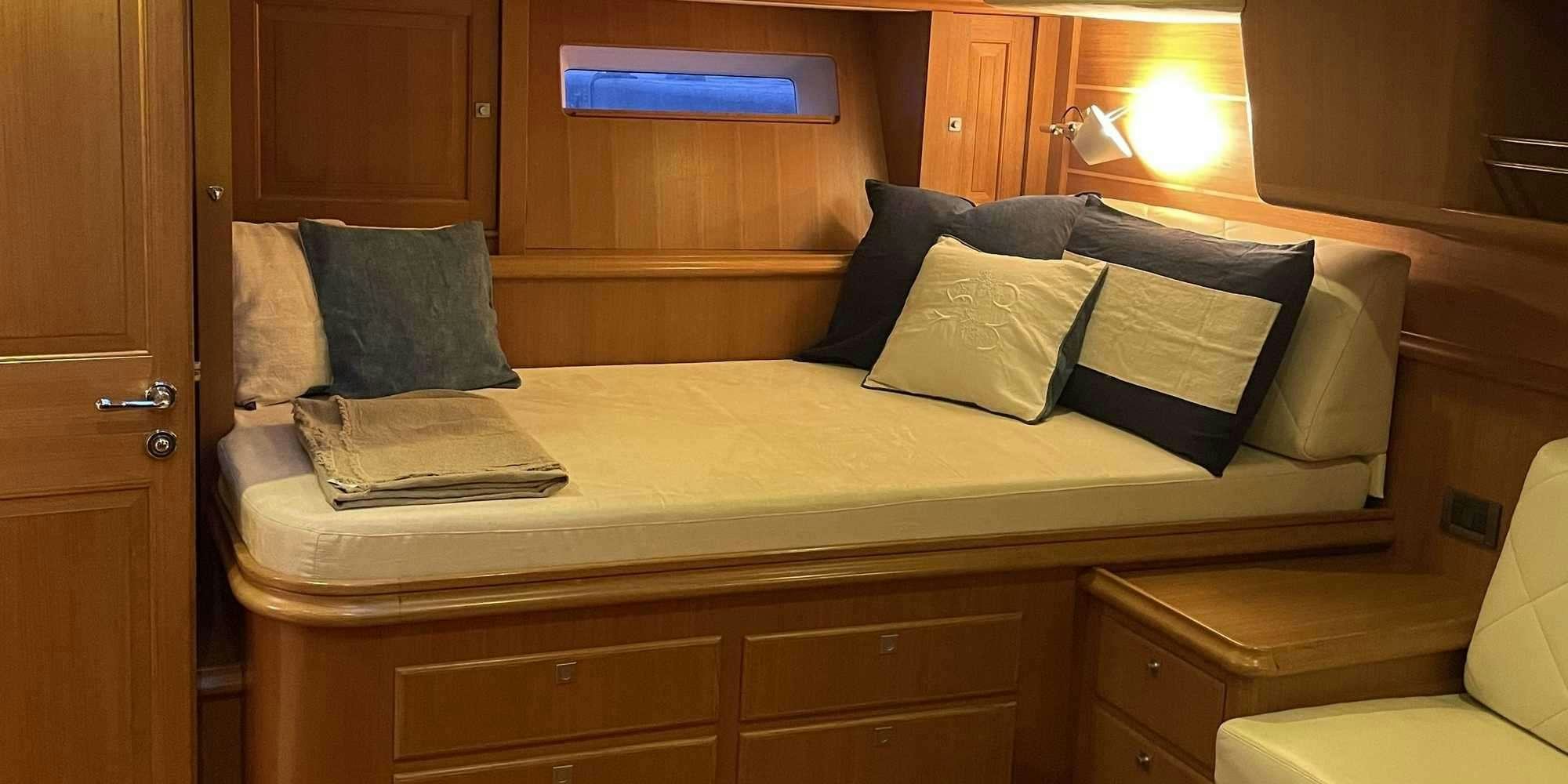 a bed with pillows and a chair aboard LA VIDELLE Yacht for Charter