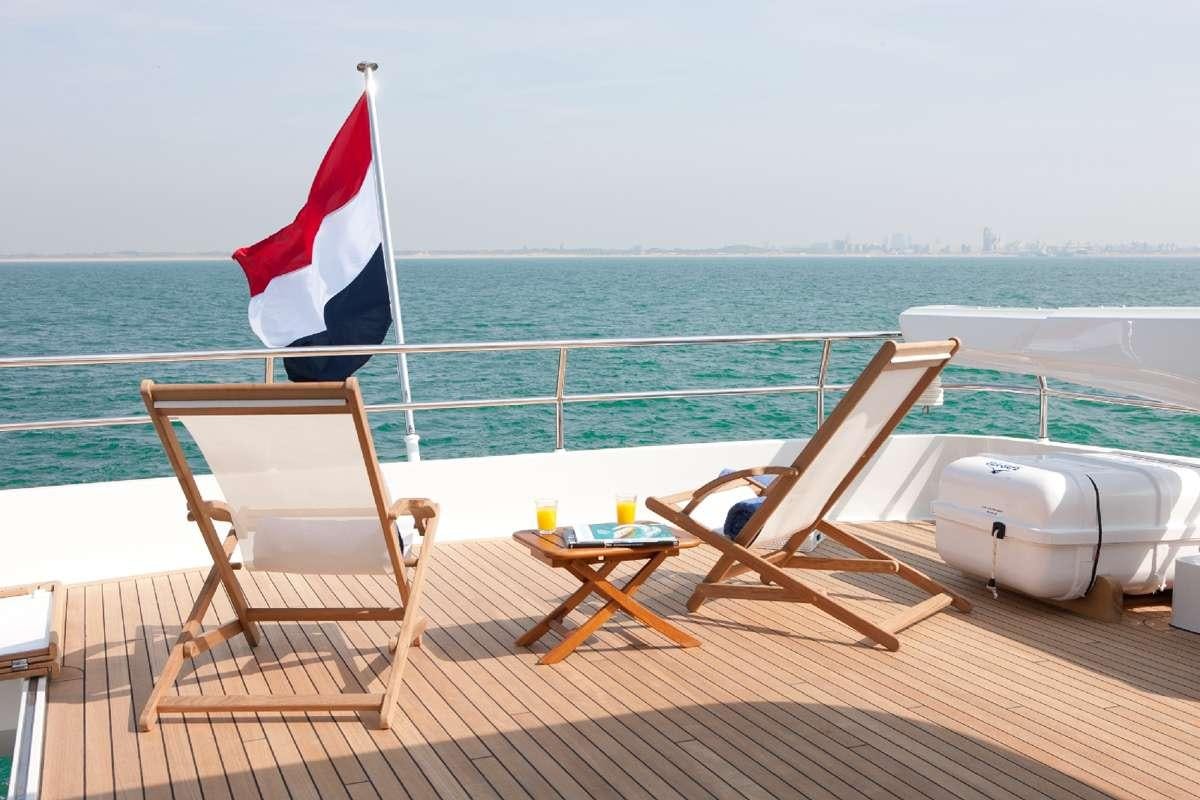 a flag on a pole on a deck overlooking a beach aboard FIREFLY Yacht for Charter