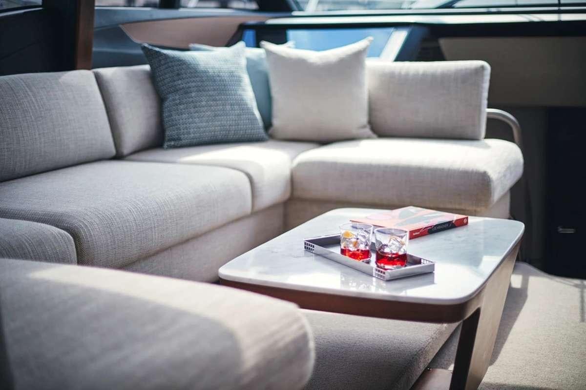 a couch with a coffee table and a glass of water on it aboard CHAMELEON III Yacht for Charter