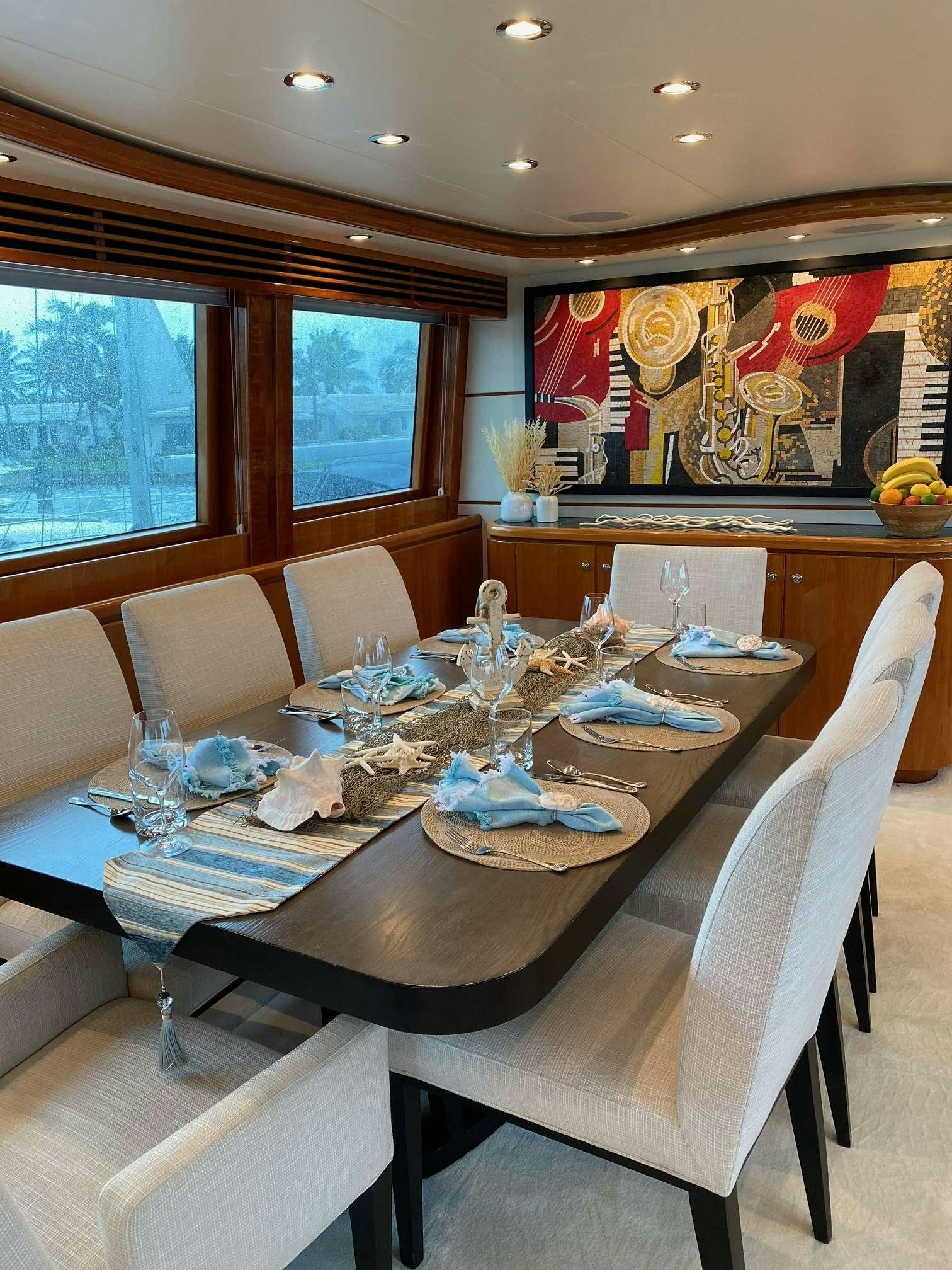 a dining table with a set of chairs and a large window aboard TRIPLE NET Yacht for Charter
