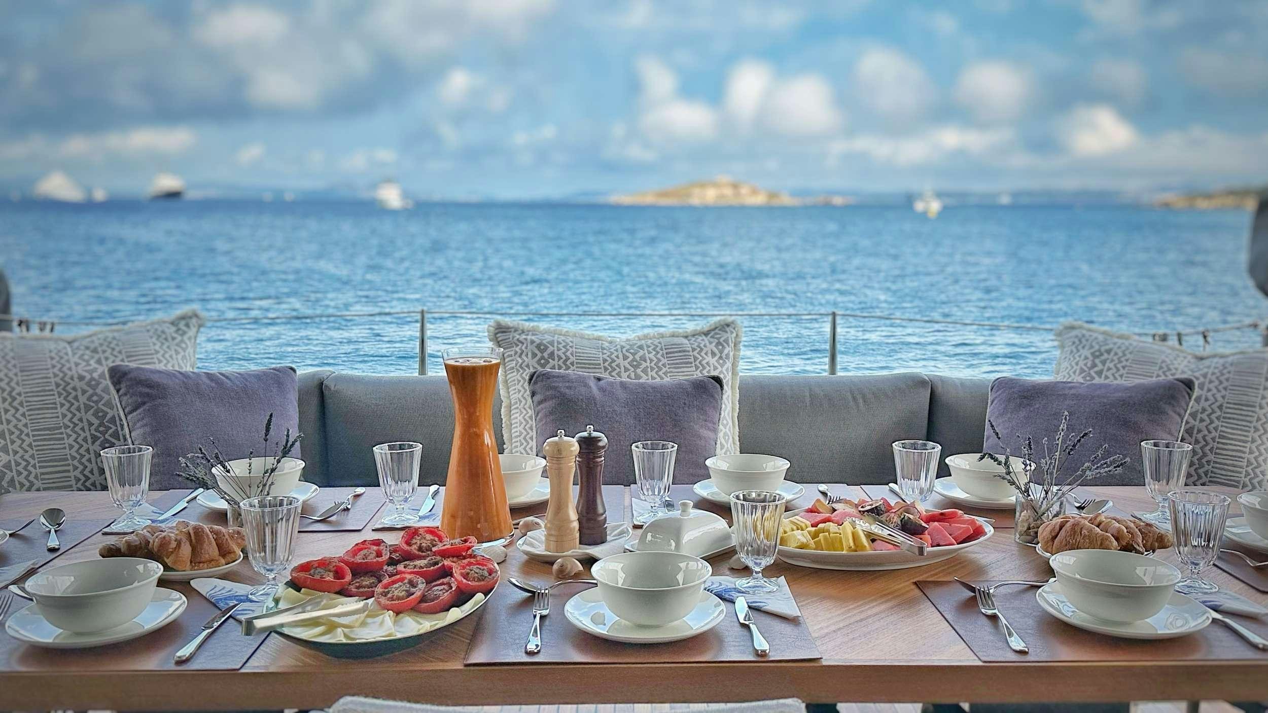 a table with food and drinks on it by a large body of water aboard VIVA LA VIDA Yacht for Charter