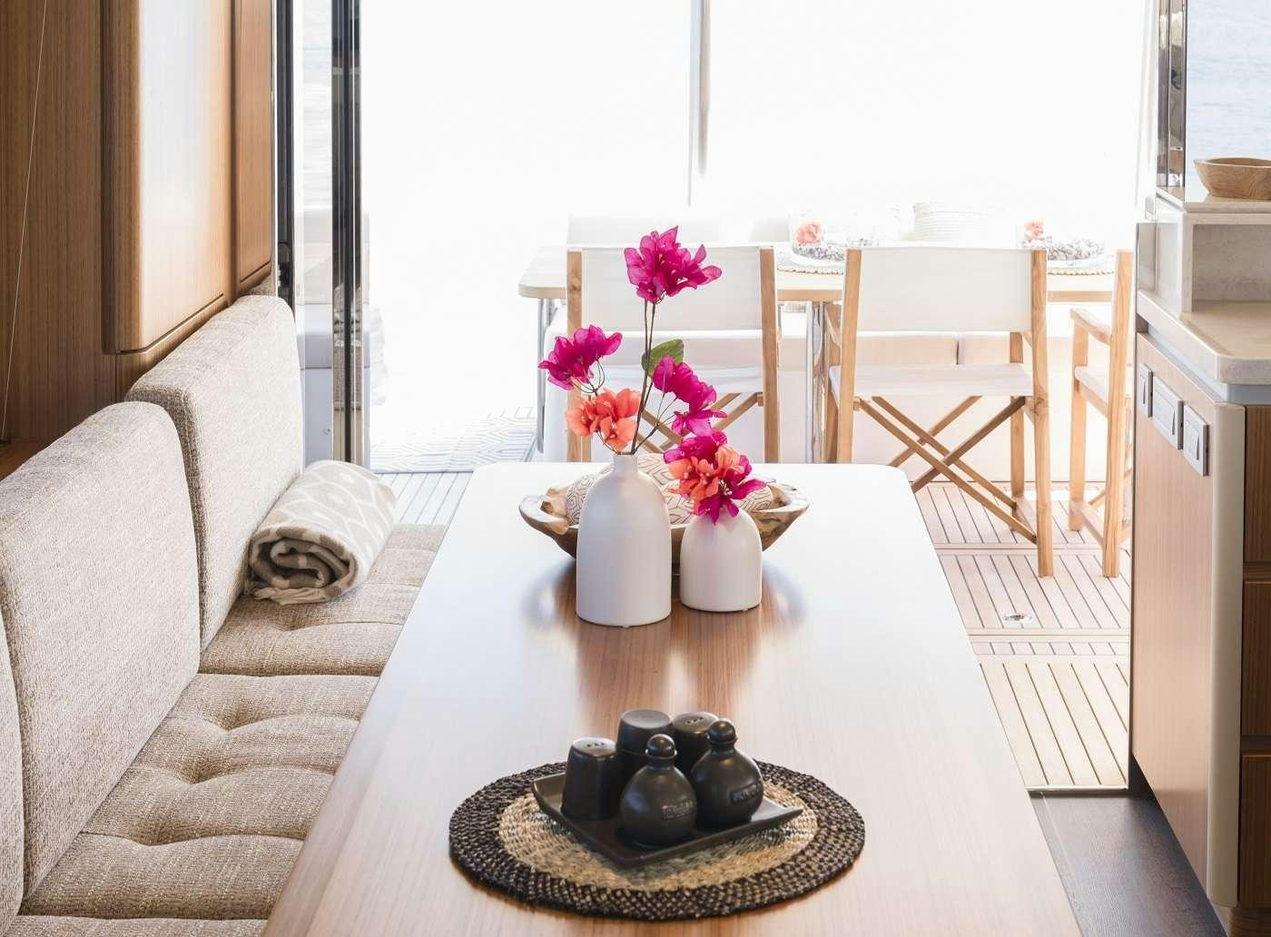 a table with a plate of food and a vase with flowers on it aboard SIR HENDRIK Yacht for Charter