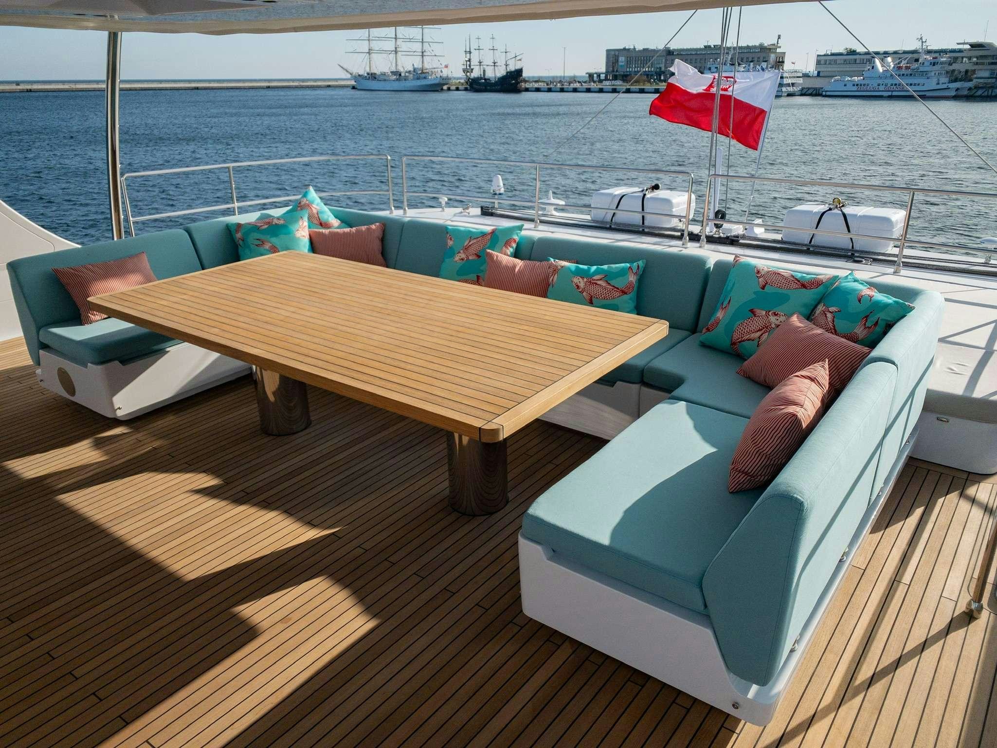 a couch and a table on a deck overlooking a body of water aboard SUNREEF 80 FANTASTIC TOO Yacht for Charter