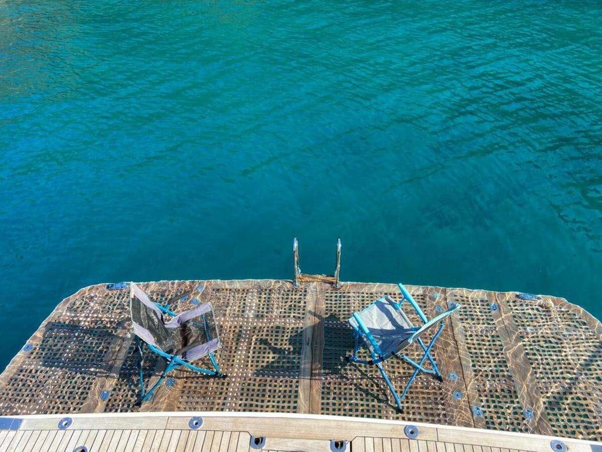 a building with a beach and chairs in the background aboard BORAM Yacht for Charter