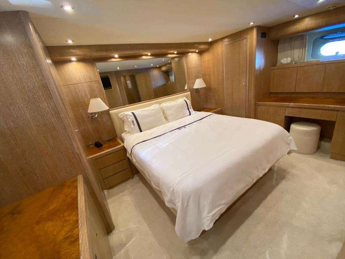 a bedroom with a bed and a wood cabinet aboard BORAM Yacht for Charter