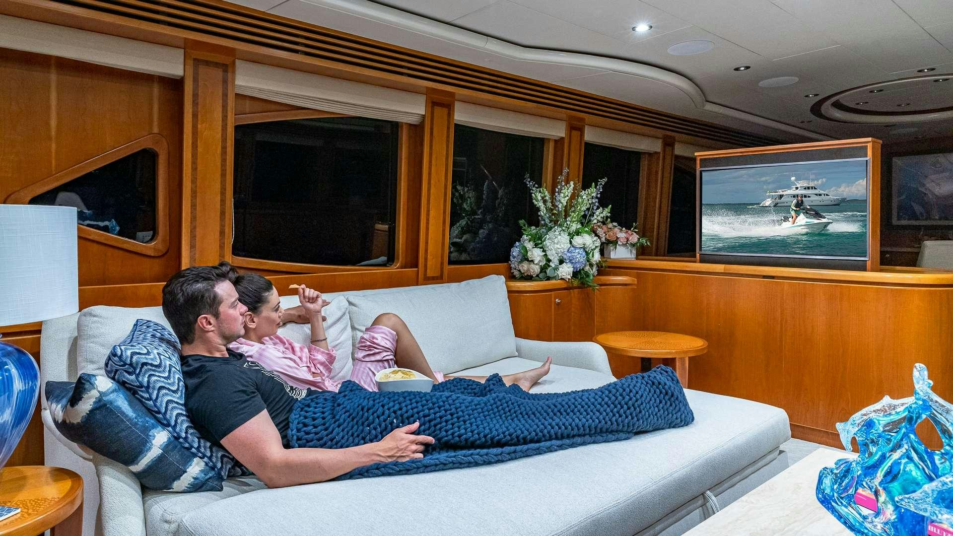 a man and a woman lying on a couch in a living room aboard B HAPPY Yacht for Charter
