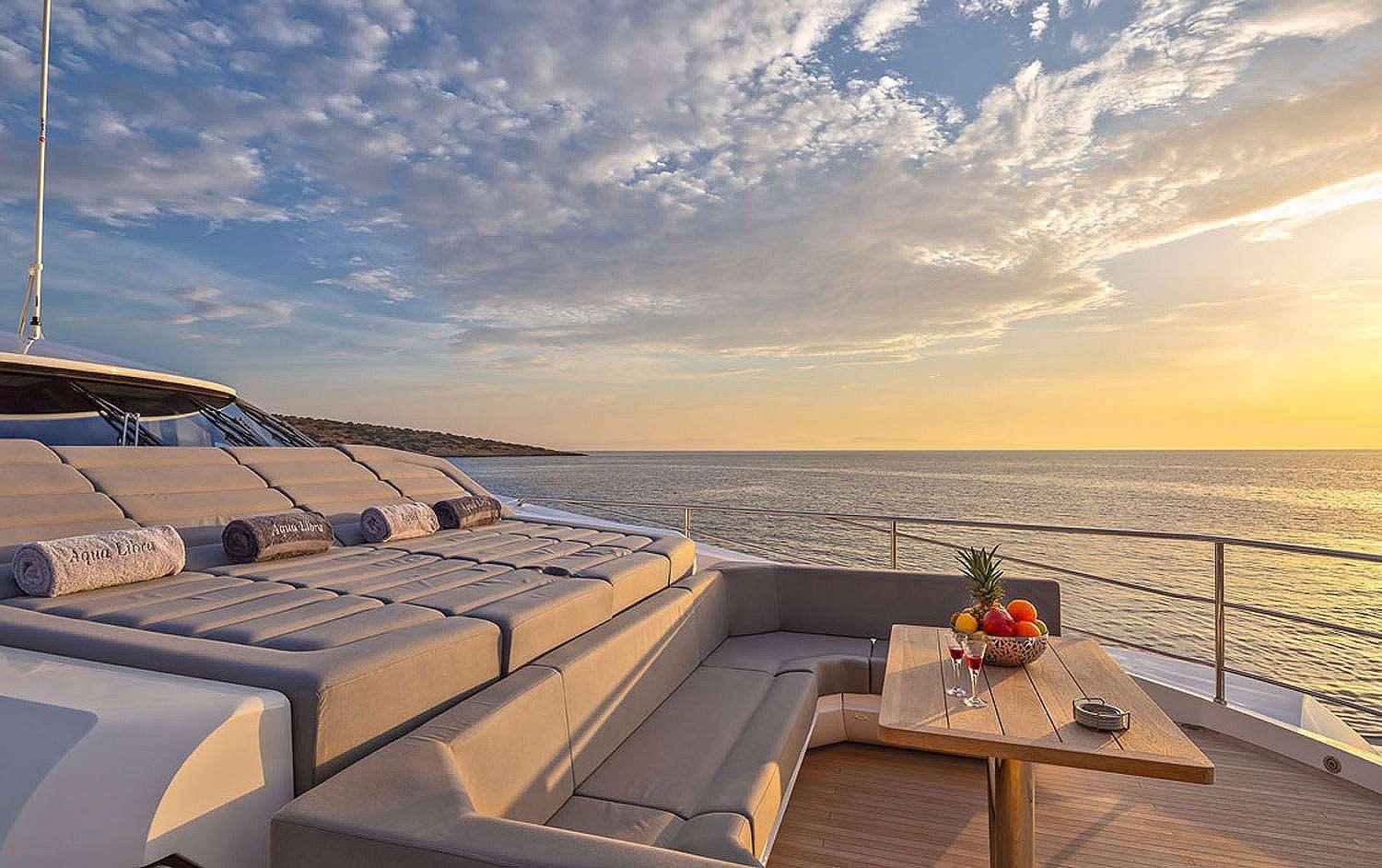 a deck with a view of the ocean and the sun setting aboard AQUA LIBRA Yacht for Charter