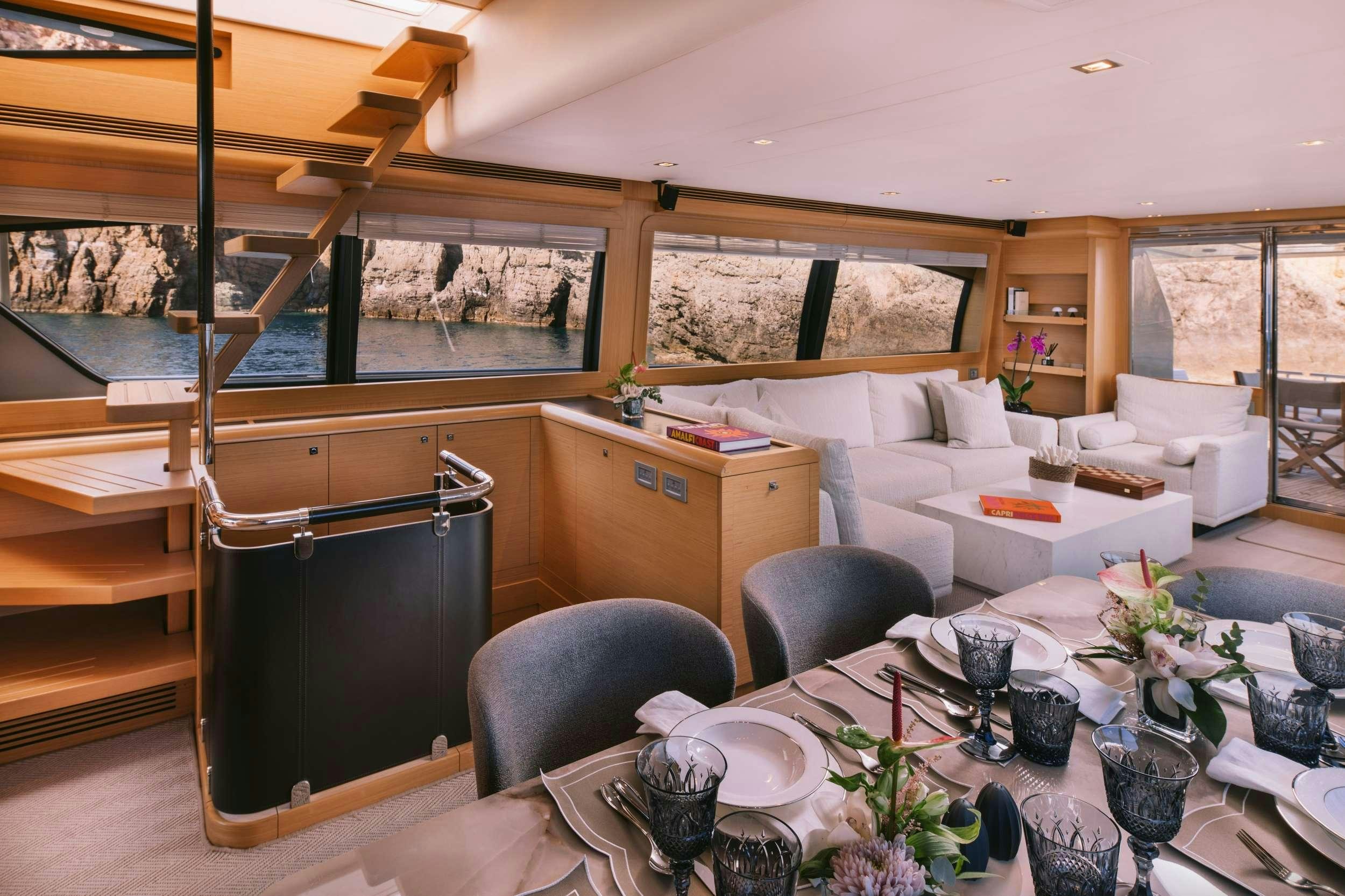 a living room with a large black refrigerator and a table aboard D&AMP;D Yacht for Charter