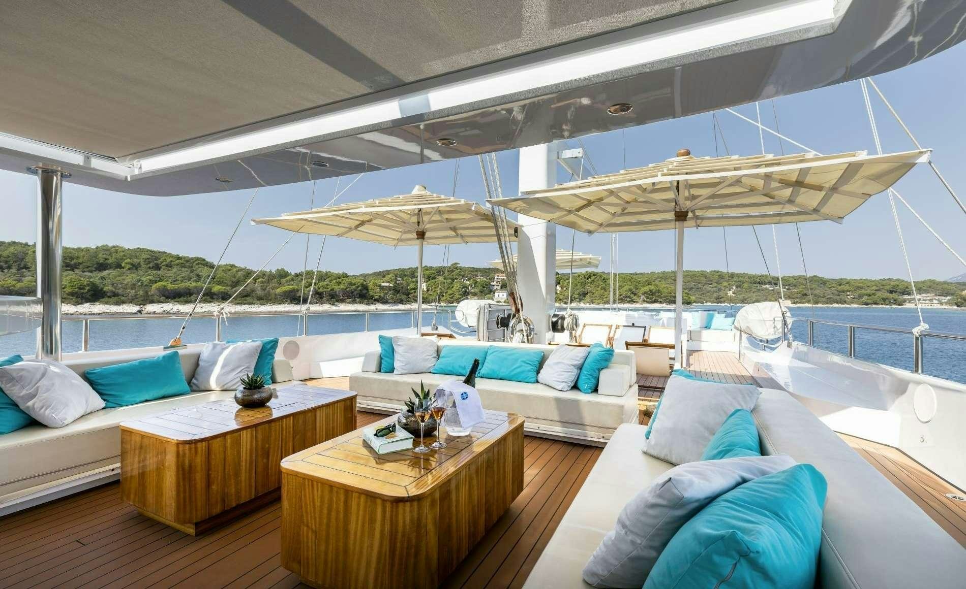a room with a couch and a table and a large umbrella aboard OMNIA Yacht for Charter