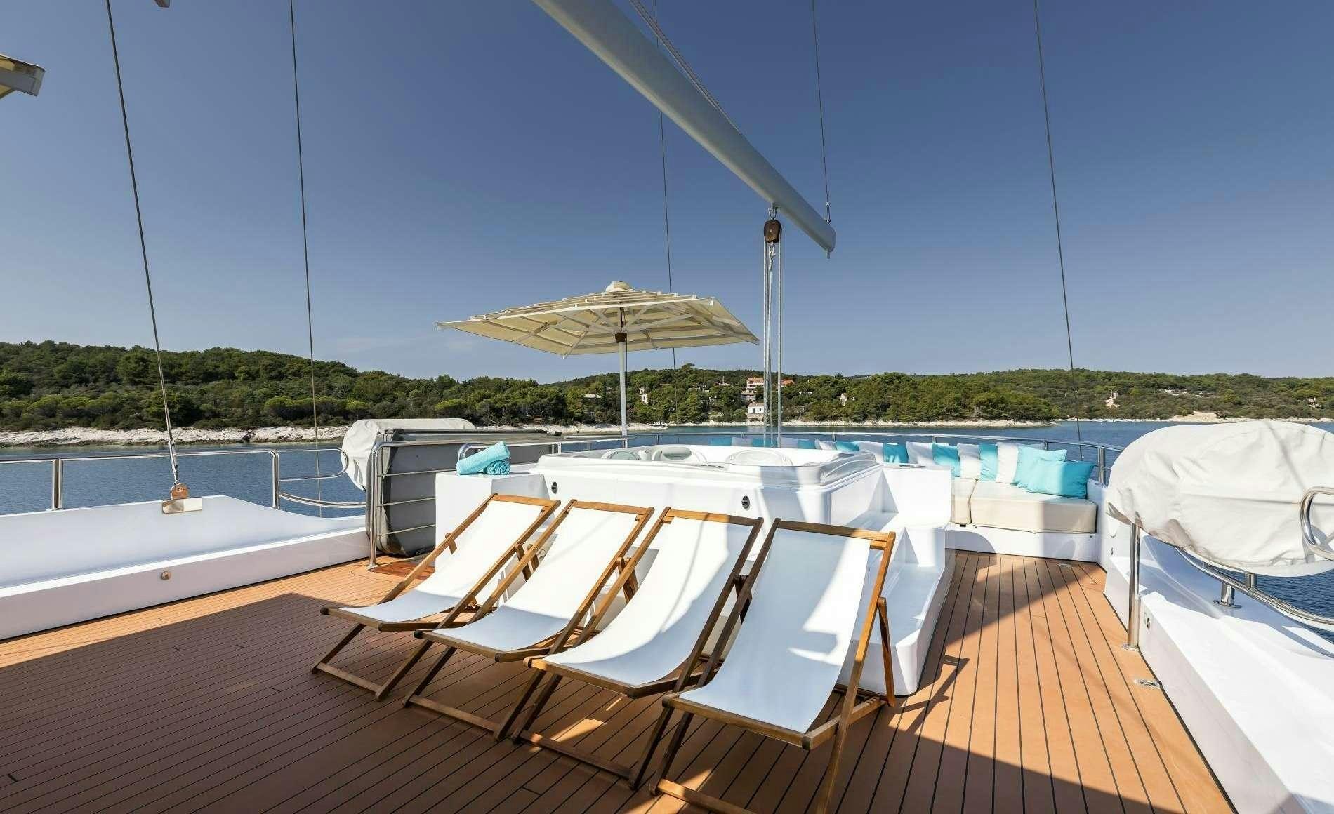 a deck with a view of a boat and umbrellas on it aboard OMNIA Yacht for Charter