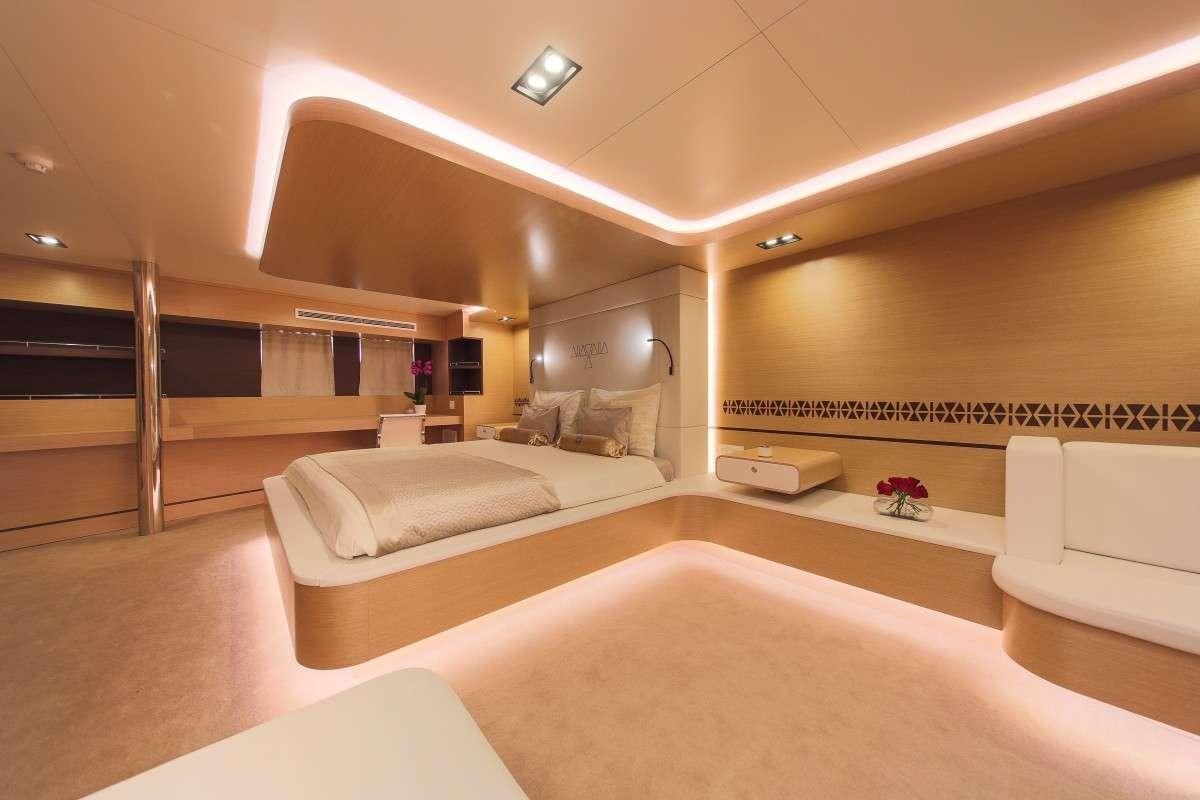a room with a bed and a desk aboard OMNIA Yacht for Charter