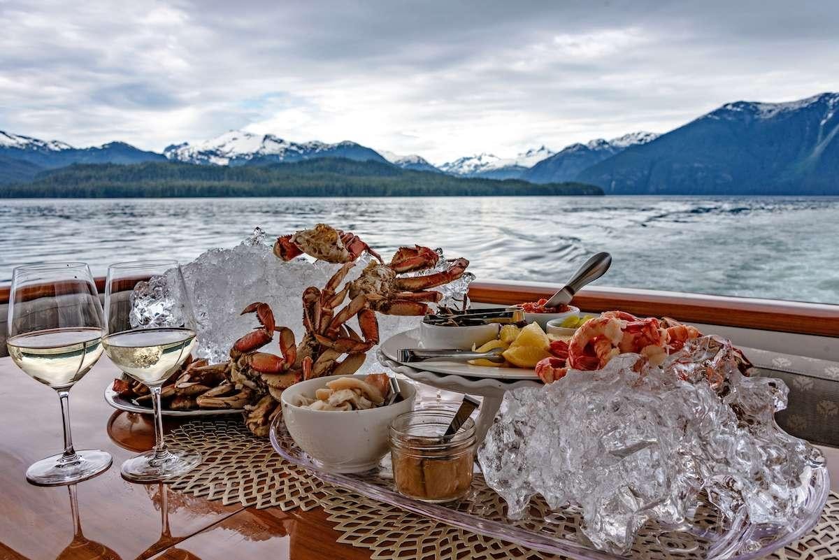a table with food and drinks on it by a body of water aboard DAUNTLESS Yacht for Charter