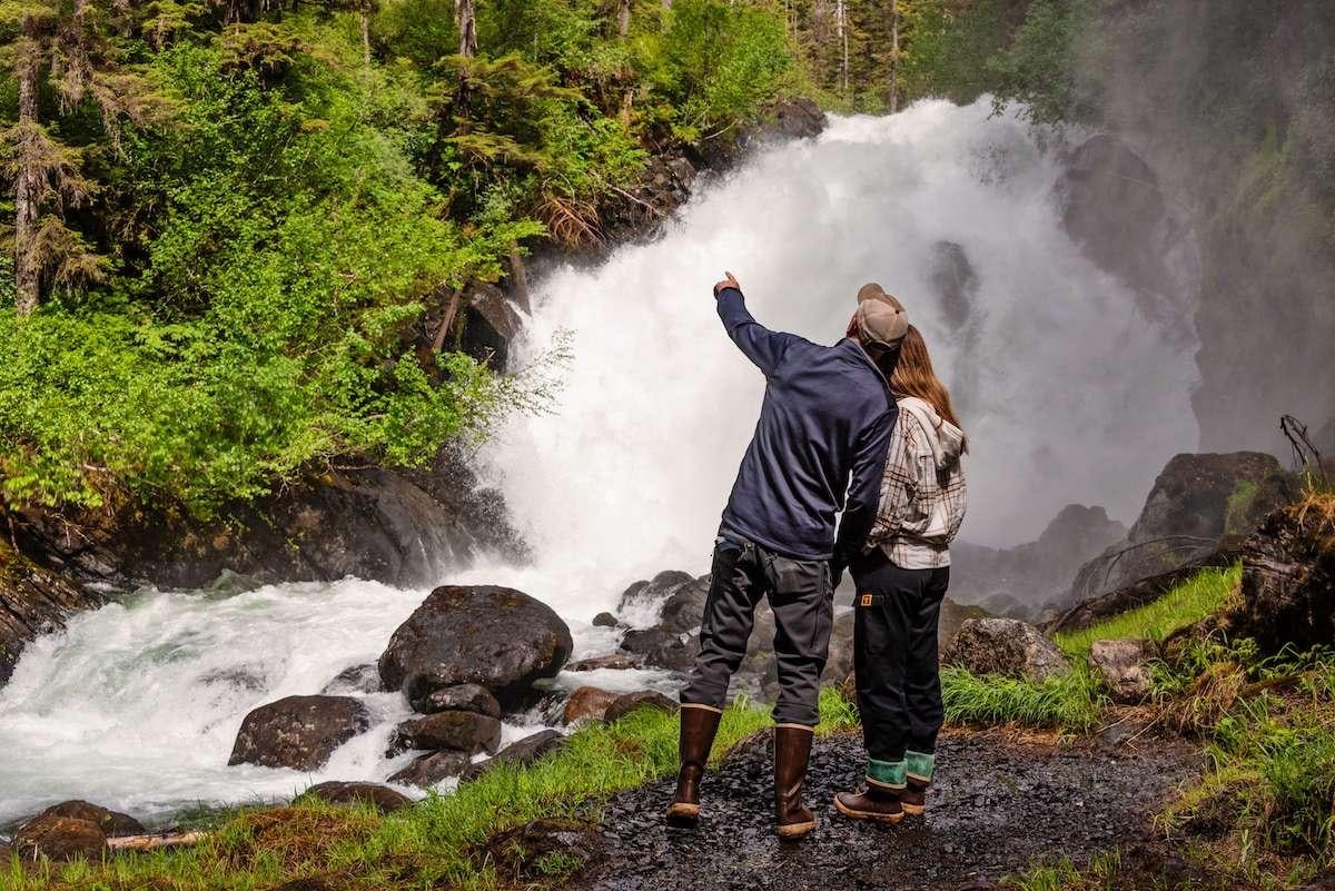 a man and woman standing next to a waterfall aboard DAUNTLESS Yacht for Charter