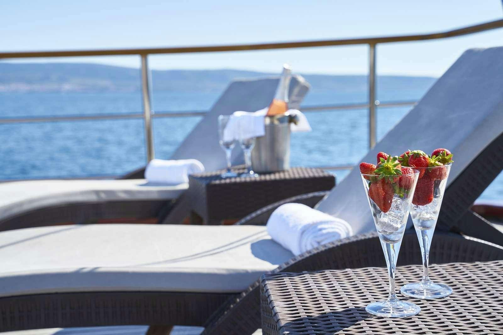 a table with a glass of wine and a tray of food on it aboard CATALEYA Yacht for Charter