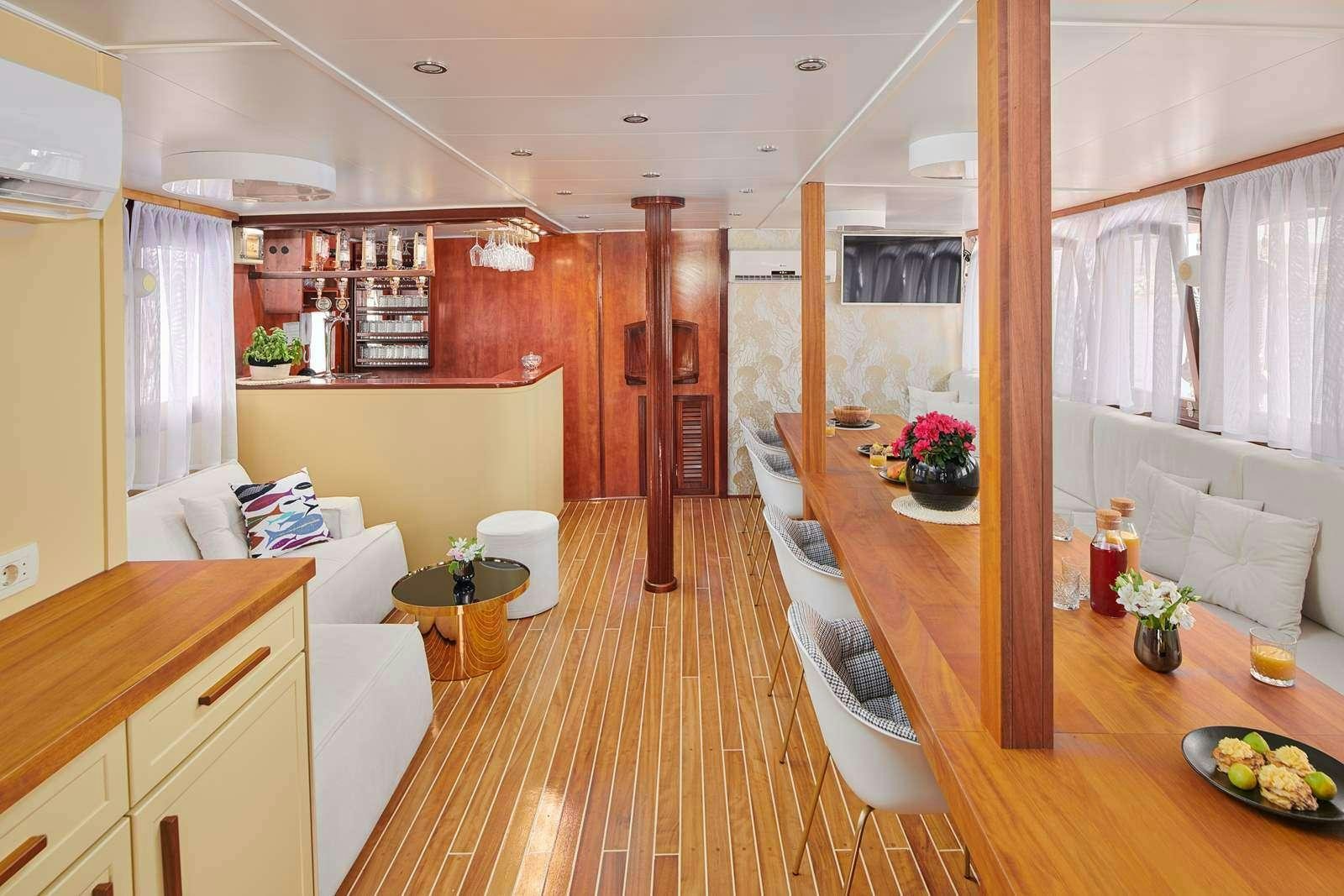 a room with a wood floor and a table with chairs and a couch aboard CATALEYA Yacht for Charter