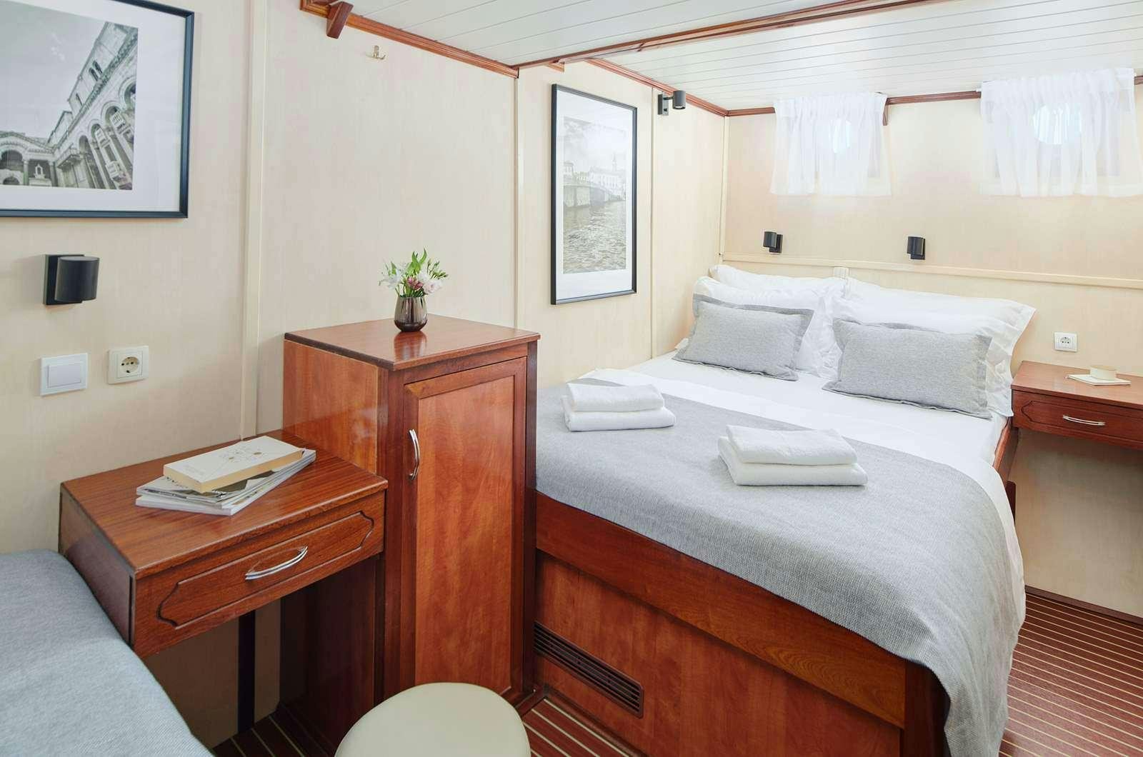 a bed with a white sheet and a wooden headboard aboard CATALEYA Yacht for Charter
