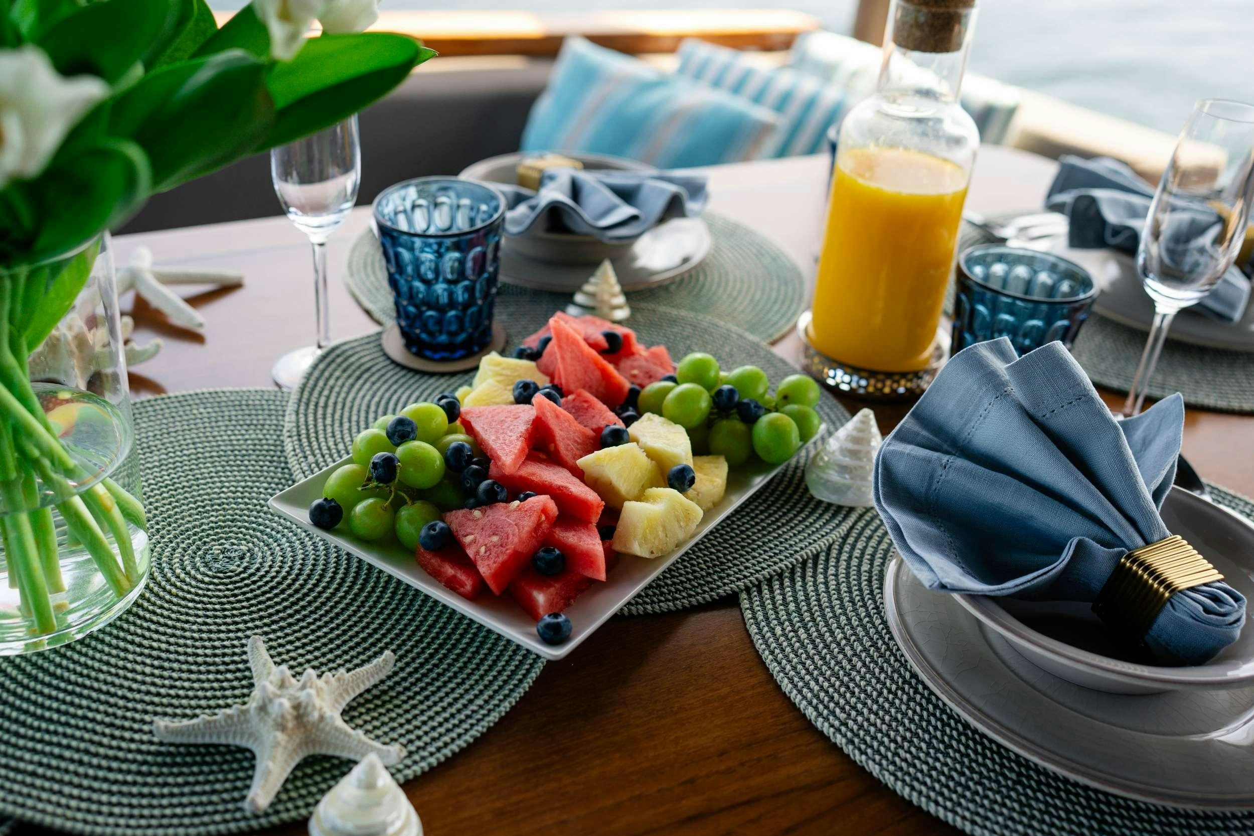 a plate of food and a glass of juice on a table aboard AMMONITE Yacht for Charter