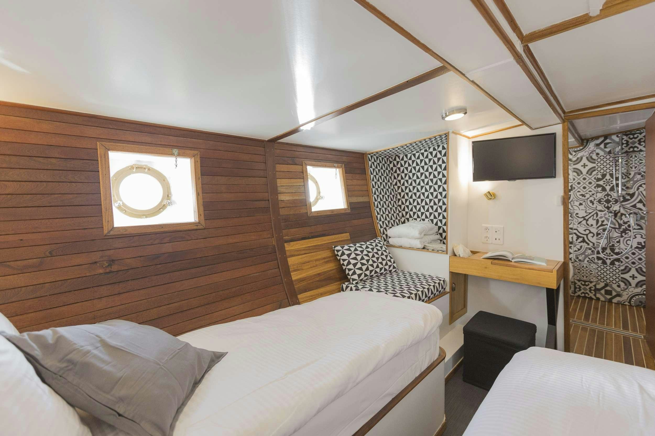 a room with a bed and a tv aboard COSMOS Yacht for Charter