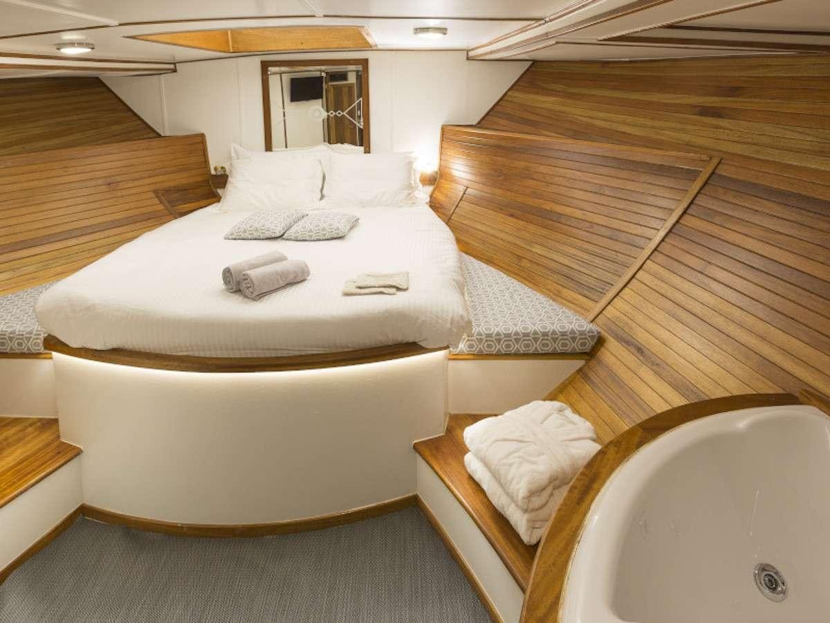 a bed with a wooden frame aboard COSMOS Yacht for Charter