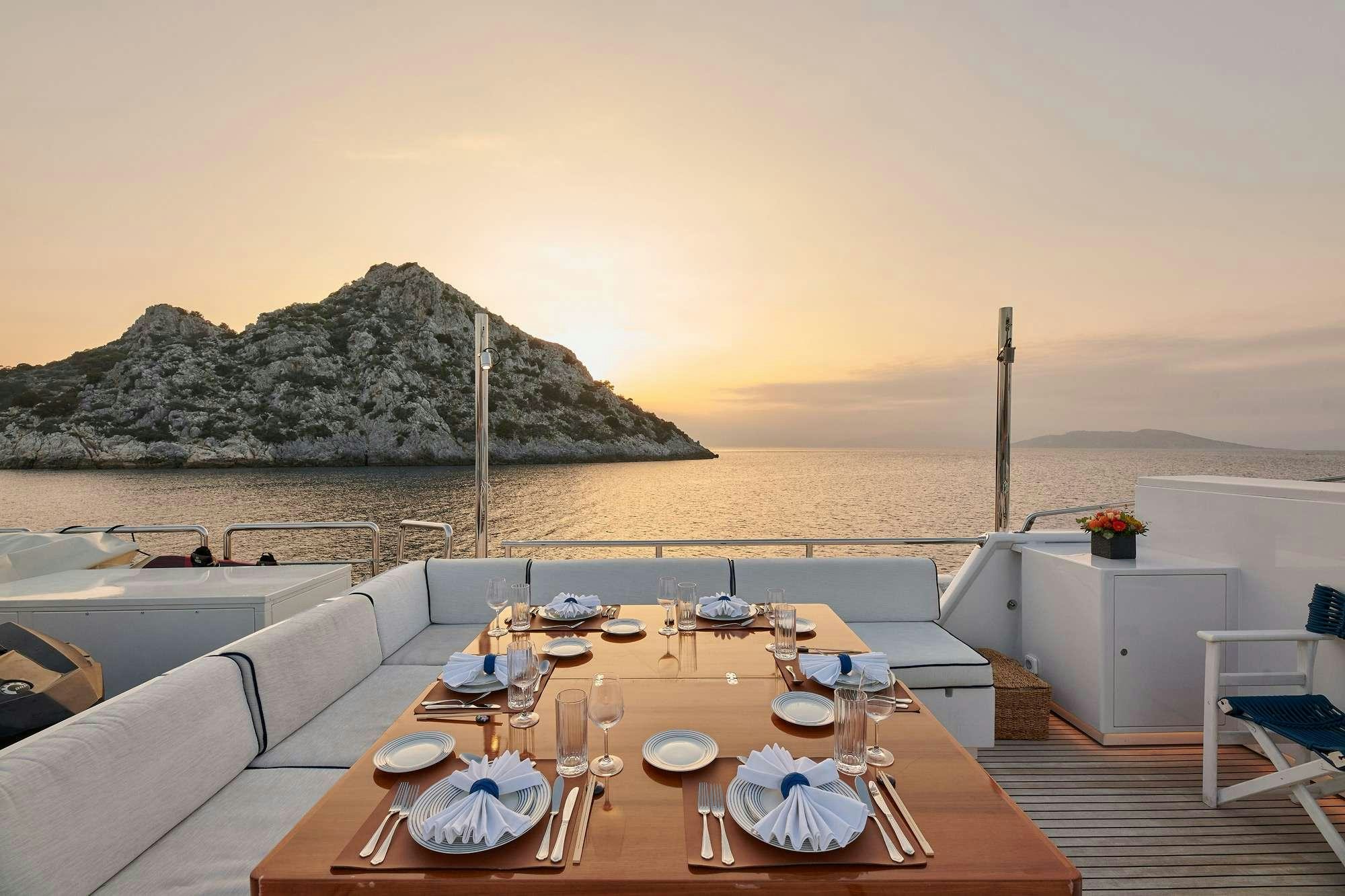 a table set for a meal on a deck overlooking a large body of water aboard ALAYA Yacht for Charter