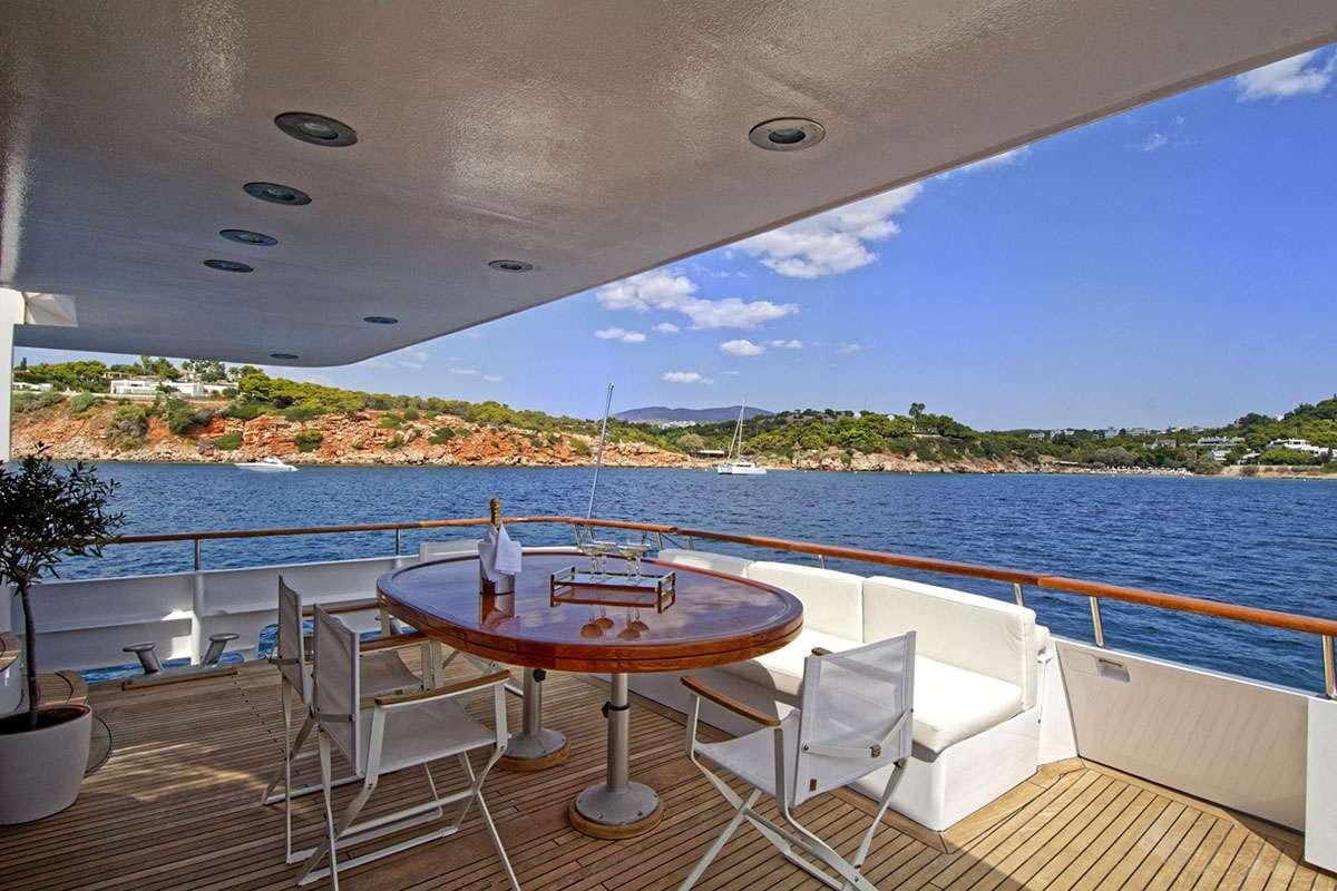 a table and chairs on a deck overlooking a body of water aboard KARMA Yacht for Charter
