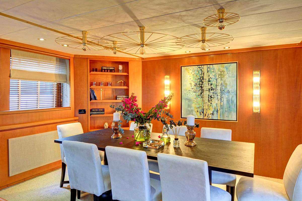a dining table with chairs and a large window aboard KARMA Yacht for Charter
