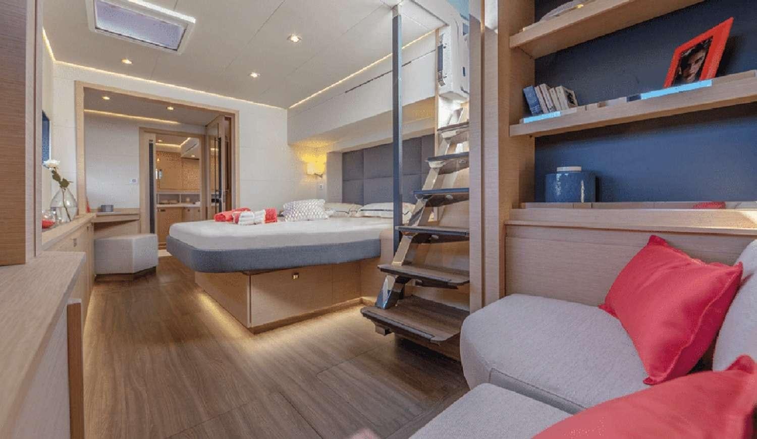 a room with a bed and a shelf with books on it aboard LOOMA Yacht for Charter