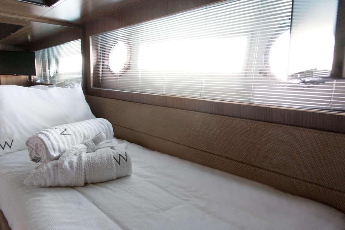 a bed with a white pillow aboard W Yacht for Charter