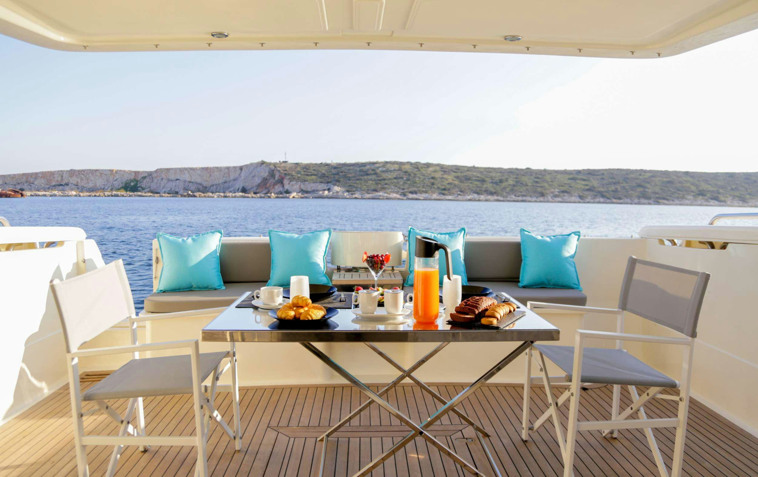 a table with chairs and a view of the ocean aboard SUMMER CAMP Yacht for Charter