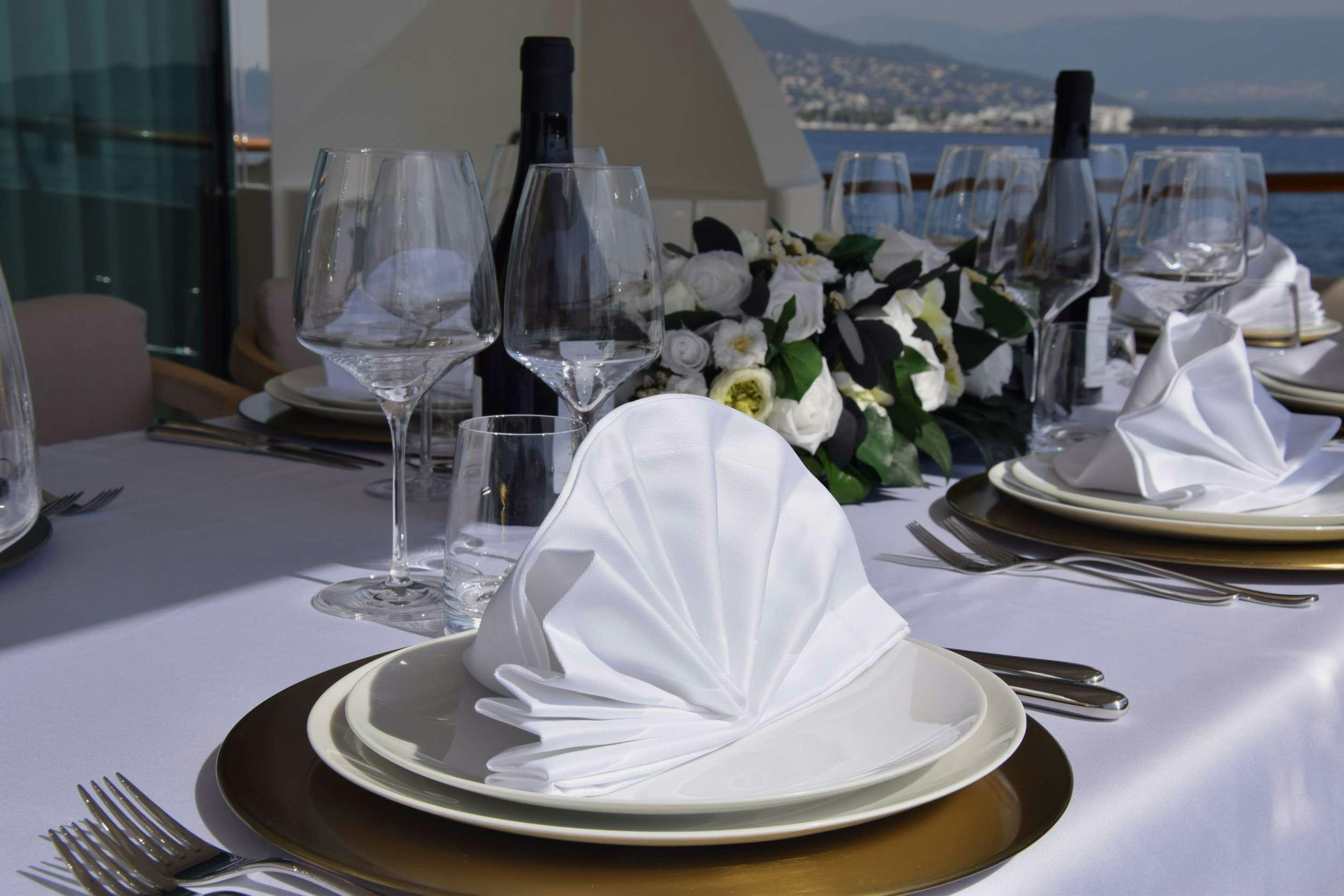 a white cake with white frosting on a white plate with a white flower on it aboard ORIZZONTE Yacht for Charter